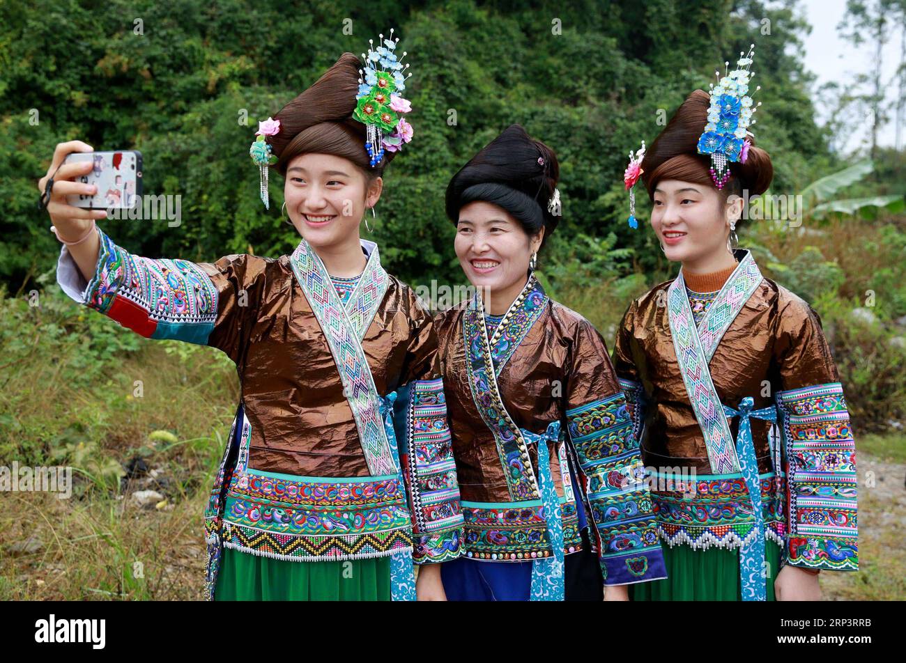 (181015) -- RONGSHUI, 15. Oktober 2018 (Xinhua) -- Frauen der Miao-ethnischen Gruppe in Liang BU-Kleidung nehmen Selfie im Huangnai-Dorf der Miao-ethnischen Gruppe in Hongshui Township des autonomen Komitats Rongshui Miao, südchinesische autonome Region Guangxi Zhuang, am 14. Oktober 2018. Liang BU, benannt nach seinem glitzernden Aussehen, ist eine Art traditionelles handgefertigtes Tuch der Miao-Ethnie. Aufgrund seiner komplizierten Herstellungstechniken wurde die Liang BU auch nur selten in Miao zu Hause gesehen. In den letzten Jahren wird es bei den modernen Menschen allmählich wieder als Lebensstandard und Bewusstsein bevorzugt Stockfoto