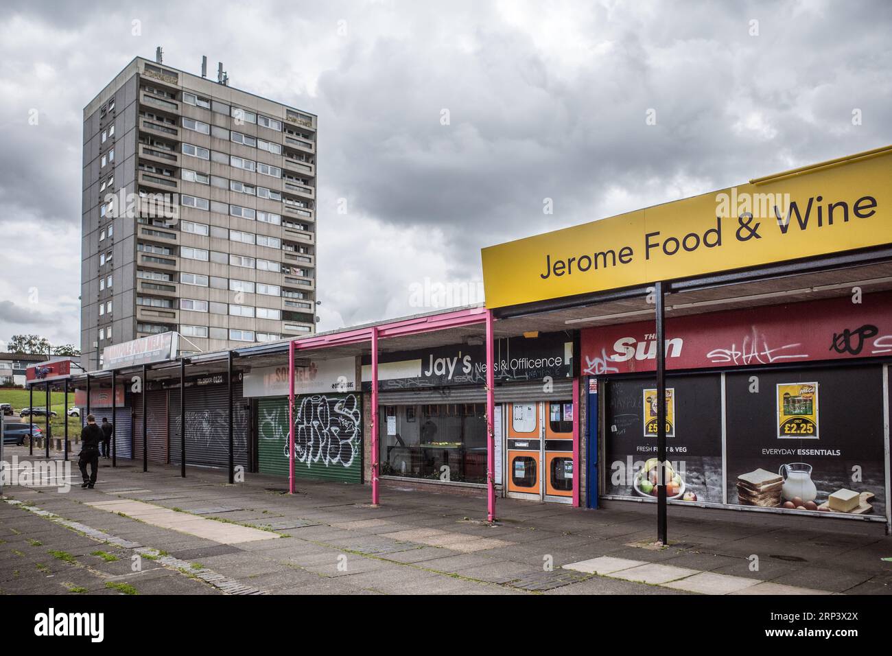 Lokales Einkaufsviertel mit heruntergekommenem Turmblock im Hintergrund. Druids Heath Housing Estate in Birmingham, Großbritannien, 2023. Stockfoto