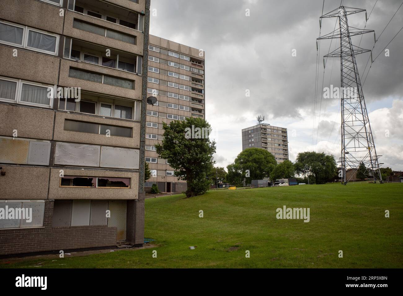 Nahaufnahme des verfallenen und heruntergekommenen Turmblocks mit anderen Blöcken und Pylon im Hintergrund. Druids Heath Housing Estate, Birmingham, Großbritannien, 2023. Stockfoto