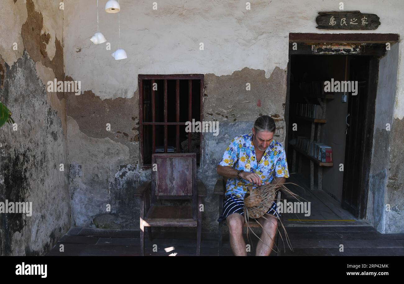 (181023) -- HAIKOU, 23. Oktober 2018 -- der Kanadier Craig Anderson macht Kunstwerke auf der Westinsel in Sanya, Südchinesische Provinz Hainan, 20. September 2018. Anderson kam im Februar auf der West Island an, wo etwa 4.000 Menschen lebten. Die Einheimischen betrachteten Anderson als einen Schnitzer, als er zum ersten Mal ankam, als er fast jeden Tag am Strand umherwanderte und Treibholz, Plastikflaschen, zerbrochene Gläser und rostige Eisenstücke aufnahm. Im Laufe der Zeit erkannten die Einheimischen, dass Anderson ein Künstler ist, der sich dem Umweltschutz widmet. Er profitiert von der wiederverwertbaren und regenerativen Mater Stockfoto
