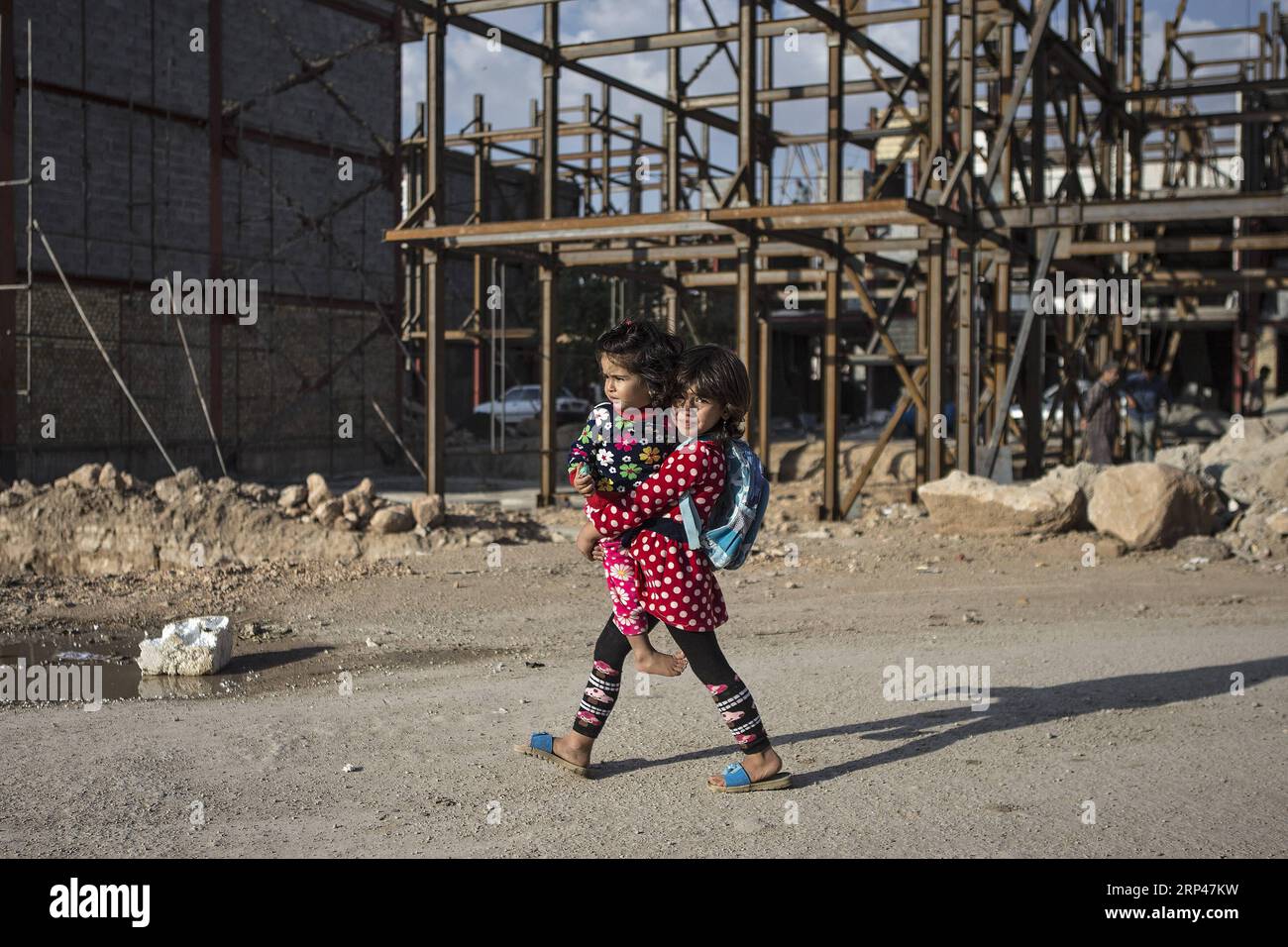 (181030) -- SARPOL-E ZAHAB (IRAN), 30. Oktober 2018 -- Ein Mädchen, das ihre kleine Schwester hält, geht nach fast einem Jahr des schmerzhaften Erdbebens in Sarpol-e Zahab, Iran, am 29. Oktober 2018 an unfertigen Gebäuden vorbei. Das Erdbeben der Stärke 7,3 traf die Provinz Kermanshah am 12. November 2017, wobei Hunderte von Menschen getötet wurden. ) (yy) IRAN-SARPOL-E ZAHAB-LEBEN NACH ERDBEBEN AhmadxHalabisaz PUBLICATIONxNOTxINxCHN Stockfoto