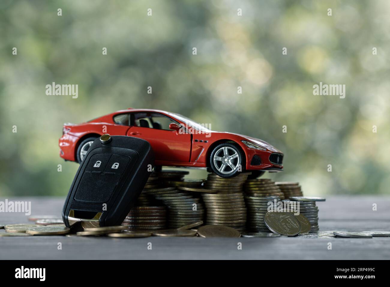 Einsparungen bei Kfz-, Finanz- und Kfz-Darlehen, Investitions- und Geschäftskonzepten. Miniatur-Automodell mit wachsendem Münzstapel auf naturgrünem bac Stockfoto