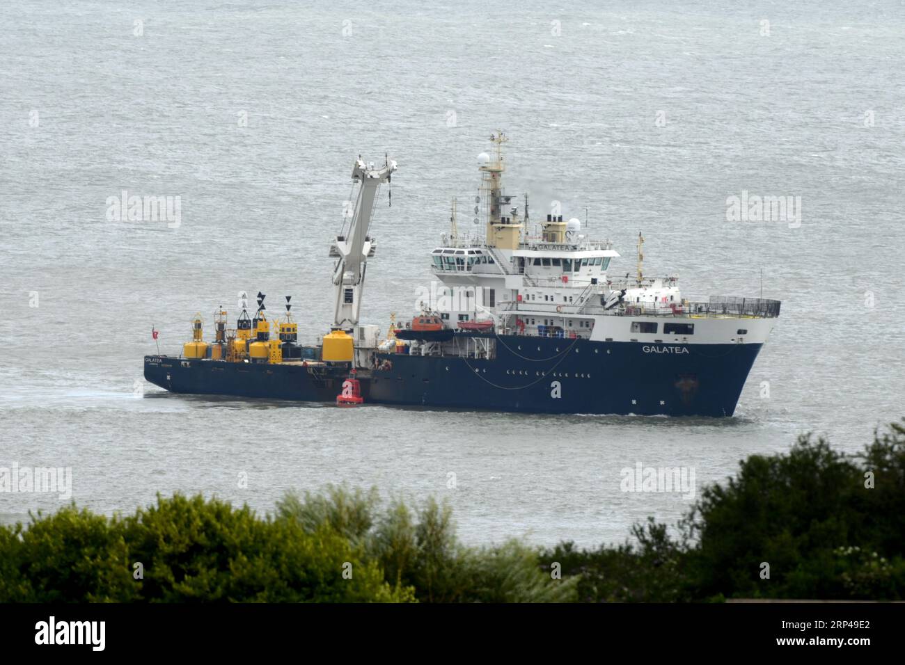 Die Galatea bringt die Mixon Boje gereinigt und kontrolliert ins Meer zurück, wo sie die Sandbank vor den Mumbles markiert. Krane senken das Leuchtfeuer Swansea, Wales Stockfoto