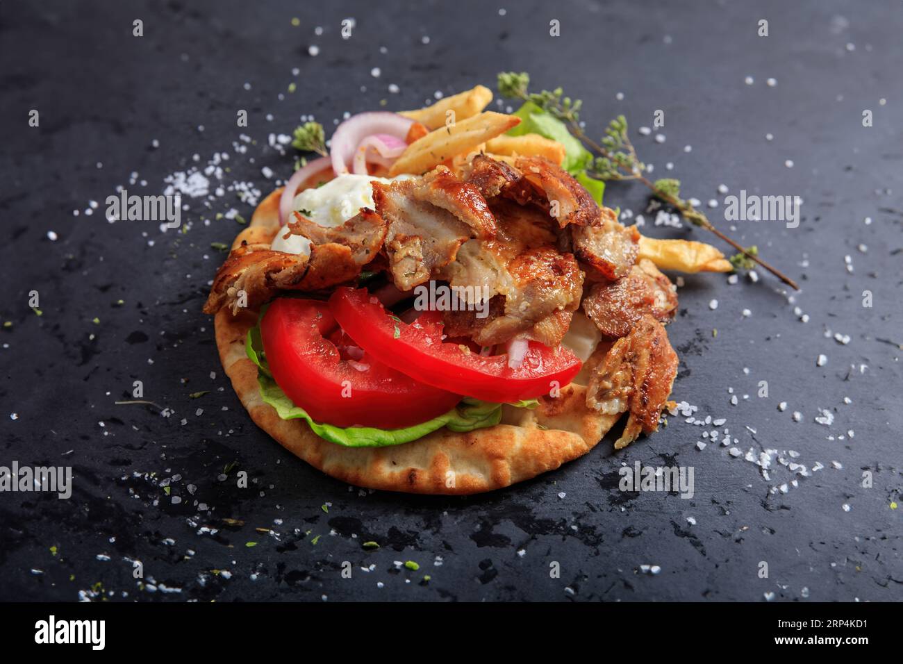 Griechisches Gyros-Gericht auf einem schwarzen Gericht. Leckeres Food-Konzept. Souvlaki, Sawarma mit Pita, Fleisch, Zwiebeln, Tomaten, Tzatziki, Kartoffel. Draufsicht Stockfoto