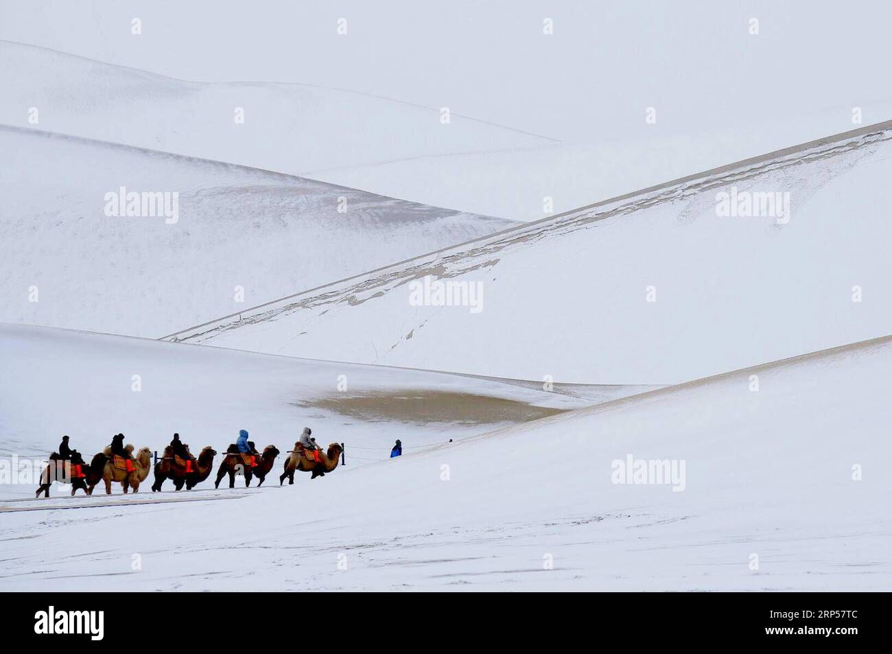 (181202) -- DUNHUANG, 2. Dezember 2018 -- Menschen besuchen den schneebedeckten malerischen Ort Mingsha Mountain und Crescent Spring in Dunhuang, nordwestchinesische Provinz Gansu, 2. Dezember 2018. Schnee ist auf die landschaftlich reizvolle Stelle gefallen und hat sie attraktiver gemacht. )(wsw) CHINA-GANSU-DUNHUANG-LANDSCHAFT (CN) ZhangxXiaoliang PUBLICATIONxNOTxINxCHN Stockfoto