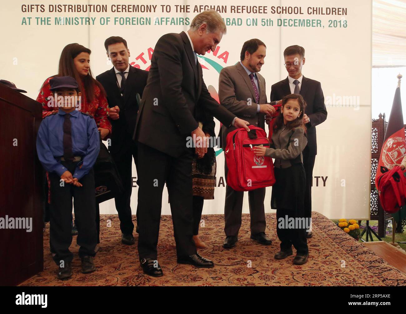 (181206) -- ISLAMABAD, 6. Dezember 2018 -- der pakistanische Außenminister Shah Mahmood Qureshi (C, Front) stellt einem afghanischen Flüchtlingskind während der Geschenke-Verleihzeremonie in Islamabad, der Hauptstadt Pakistans, am 5. Dezember 2018 eine Schultasche vor. Qureshi sagte am Mittwoch, dass Pakistan immer daran interessiert sei, dass China an den Bemühungen um den afghanischen Friedensprozess beteiligt sei, und er sei froh, dass China eine aktivere Rolle für die afghanische Entwicklung und den Wiederaufbau spiele. Qureshi sagte, dass er sich auf einen Besuch in Ka freue, als er an afghanische Flüchtlingskursteilnehmer, die in Pakistan leben, in einer Spendenzeremonie hier sprach Stockfoto