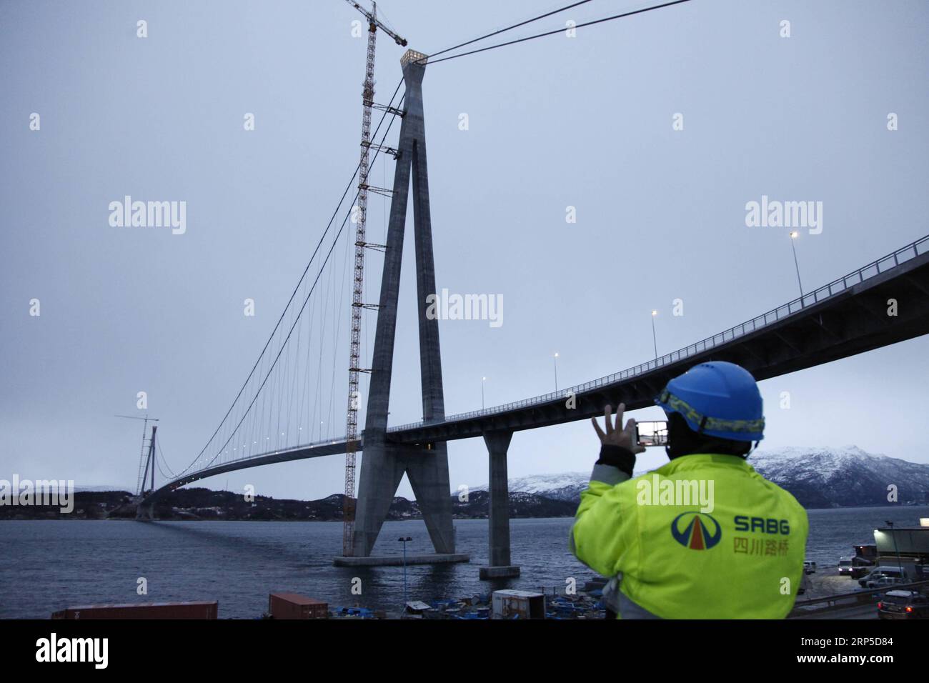 (181210) -- NARVIK, 10. Dez. 2018 (Xinhua) -- Ein chinesischer Arbeiter fotografiert die Halogaland-Brücke in der Nähe von Norwegens nördlicher Hafenstadt Narvik, 9. Dez. 2018. Am Sonntag wurde die zweitgrößte Brücke Norwegens offiziell eröffnet, die von einem chinesischen Unternehmen und seinen Partnern rund 220 km innerhalb des Polarkreises gebaut wurde. Mit einer Gesamtlänge von 1.533 Metern und einer freien Spannweite von 1.145 Metern ist die Halogaland-Brücke in der Nähe von Norwegens nördlicher Hafenstadt Narvik die längste Hängebrücke innerhalb des Polarkreises. (Xinhua/Liang Youchang) NORWEGEN-NARVIK-HALOGALAND BRIDGE OPENING PUBLICATION Stockfoto