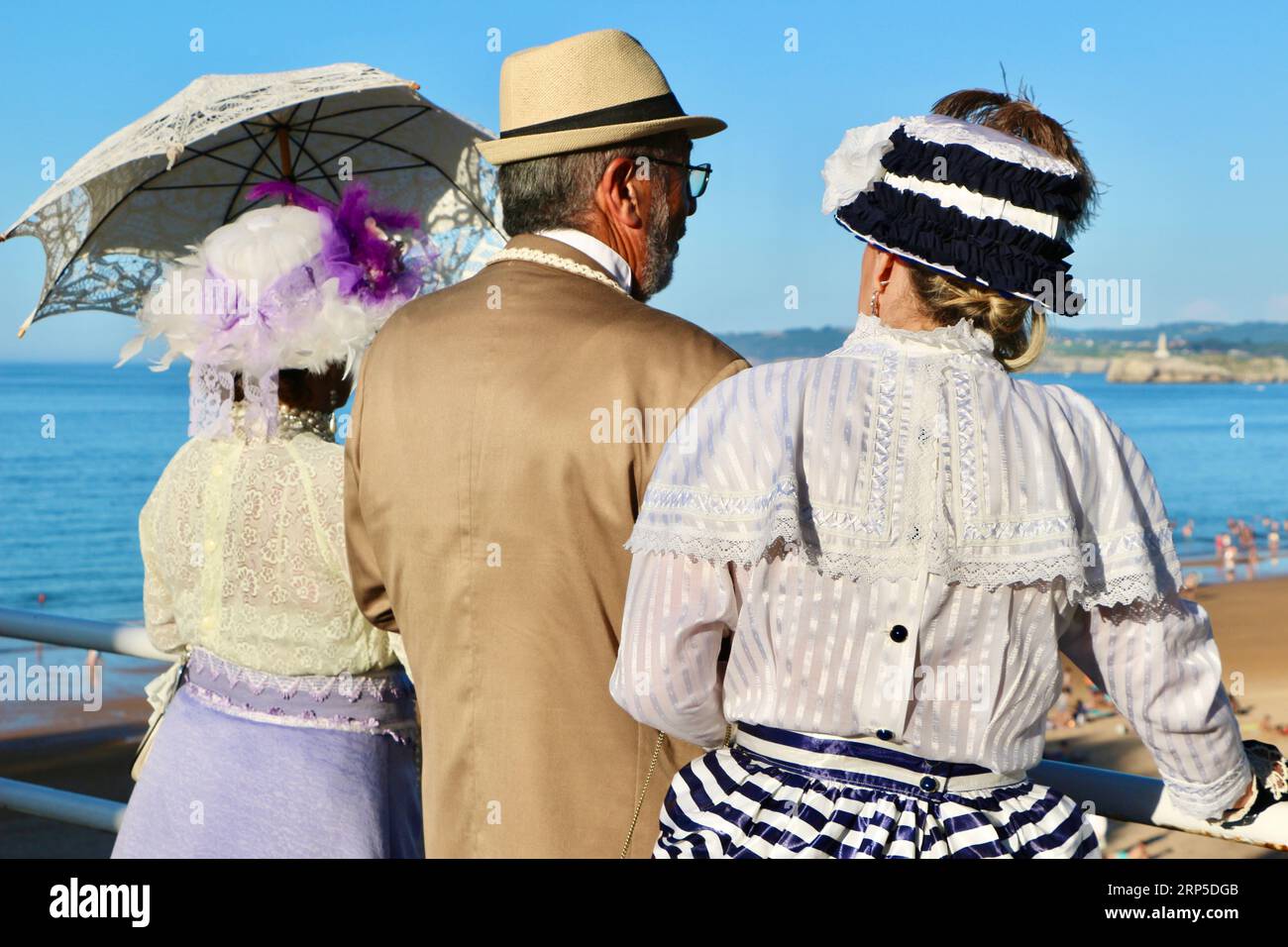 Zwei Frauen und ein Mann kleideten sich im viktorianischen Stil für die jährliche Banos de Ola-Veranstaltung Pquio Sardinero Santander Cantabria Spanien Stockfoto