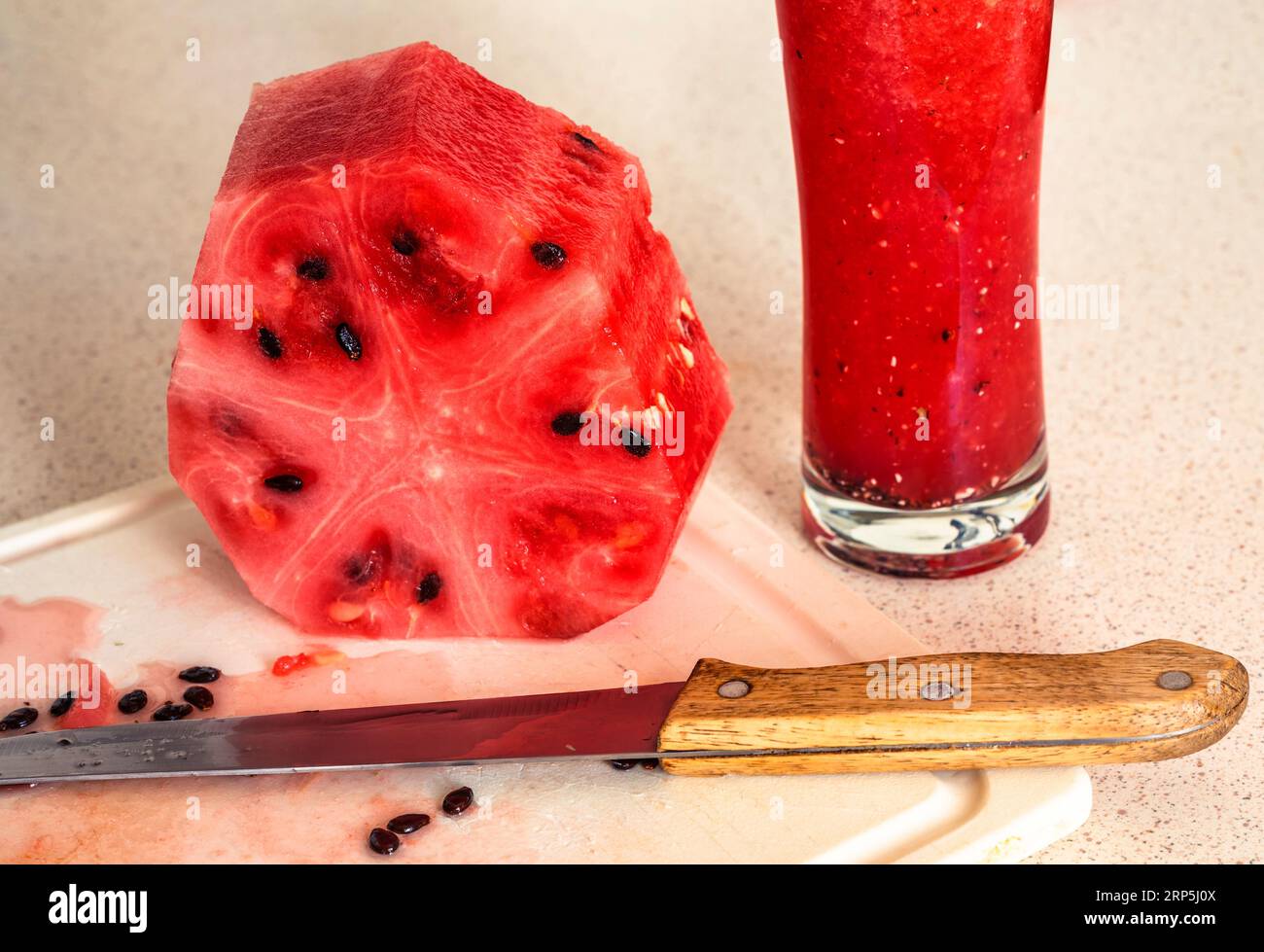 Melone in Scheiben, Messer und Mixer mit Smoothie von Melone auf Küchenbrett, Nahaufnahme. Stockfoto