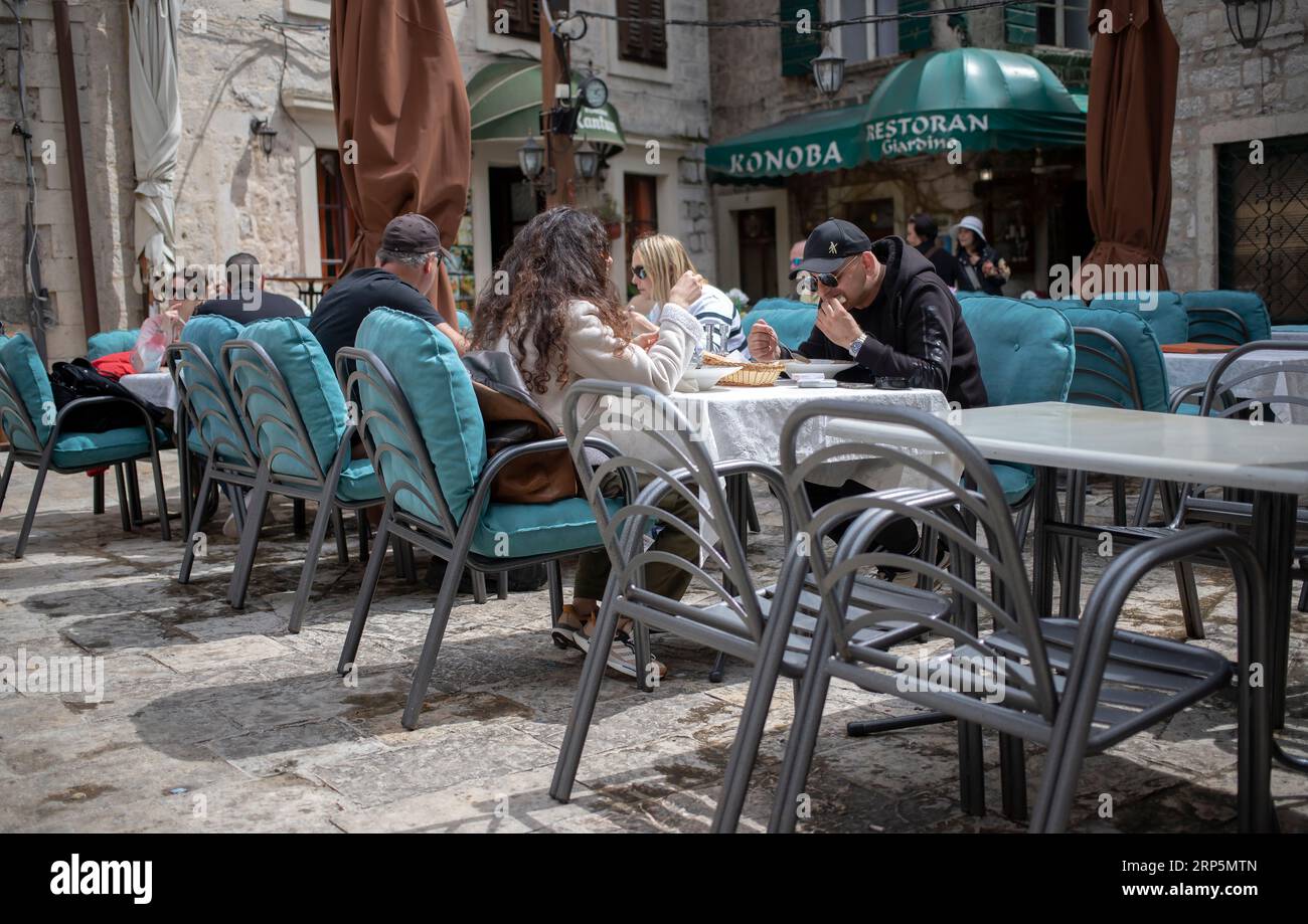 Kotor, Montenegro, 17. April 2023: Eine Gaststube im Freien mit Gästen, die am Boka Navy Square (Trg Bokeljske Mornarice) in der Altstadt speisen Stockfoto