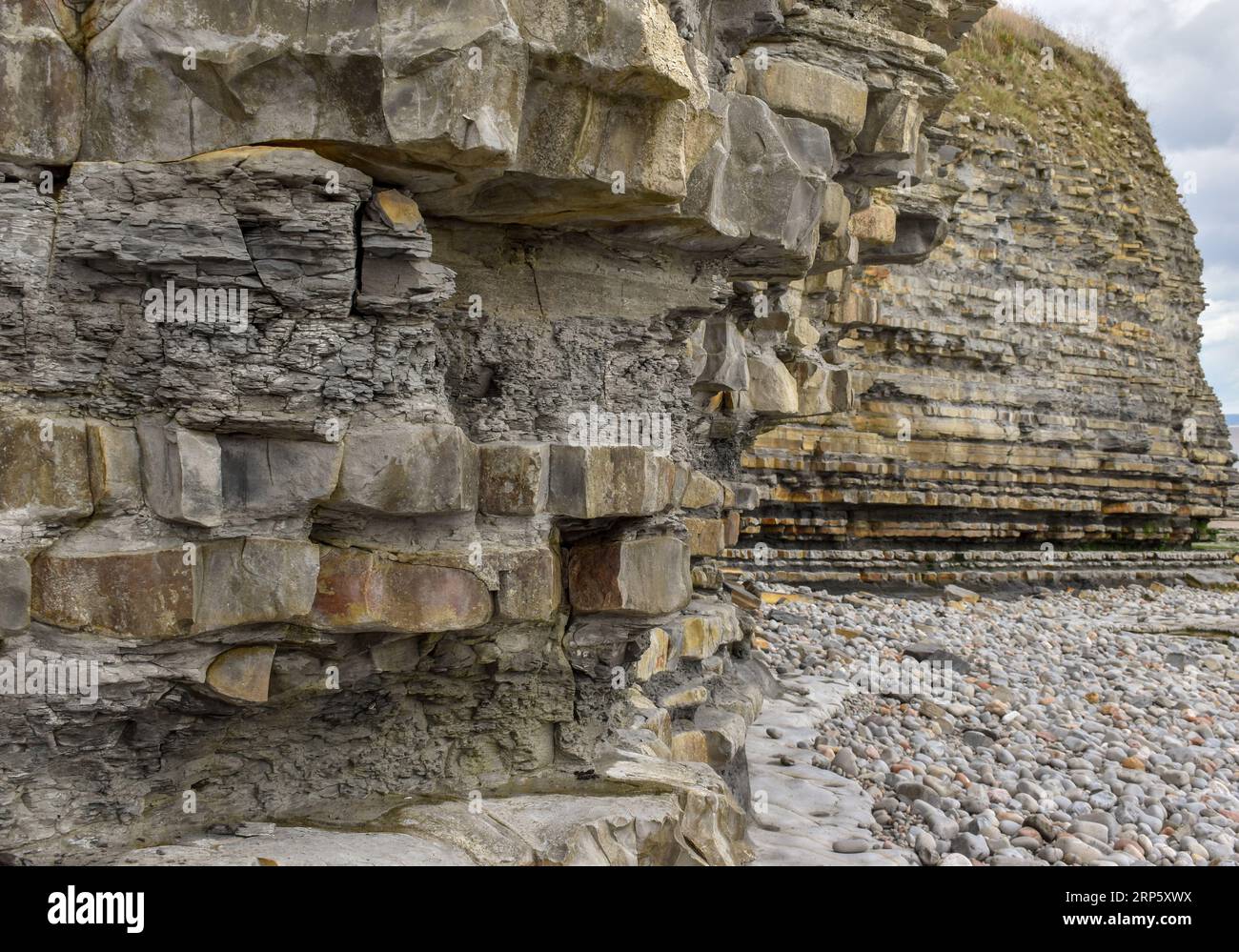 Diese Klippe an einem walisischen Strand zeigt, was die Auswirkungen der Küstenerosion und des Wetters im Laufe der Zeit auf die Felsschichten, die ihn stützen, bewirken können. Stockfoto