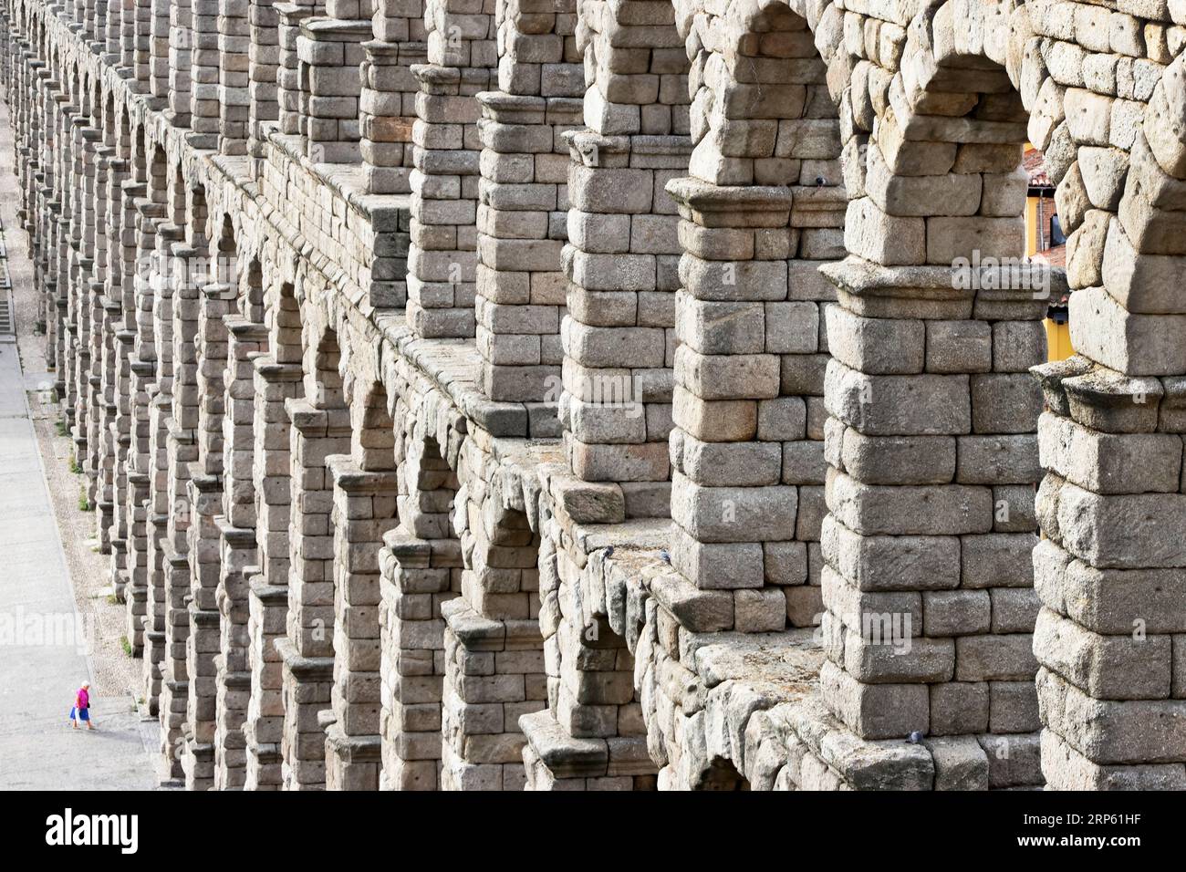 Blick auf Segovias römisches Aquädukt, mit winzigen menschlichen Figuren im Verhältnis Stockfoto