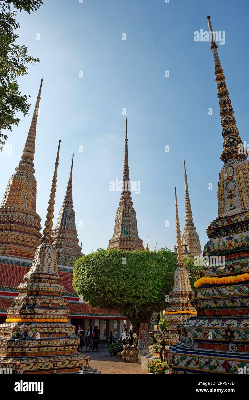 Bangkok, Thailand, 25. Dezember 2018. Ein thailändischer Tempelkomplex mit reich verzierten Chedis, die mit Gold und bunten Fliesen unter einem klaren blauen Himmel dekoriert sind. Stockfoto
