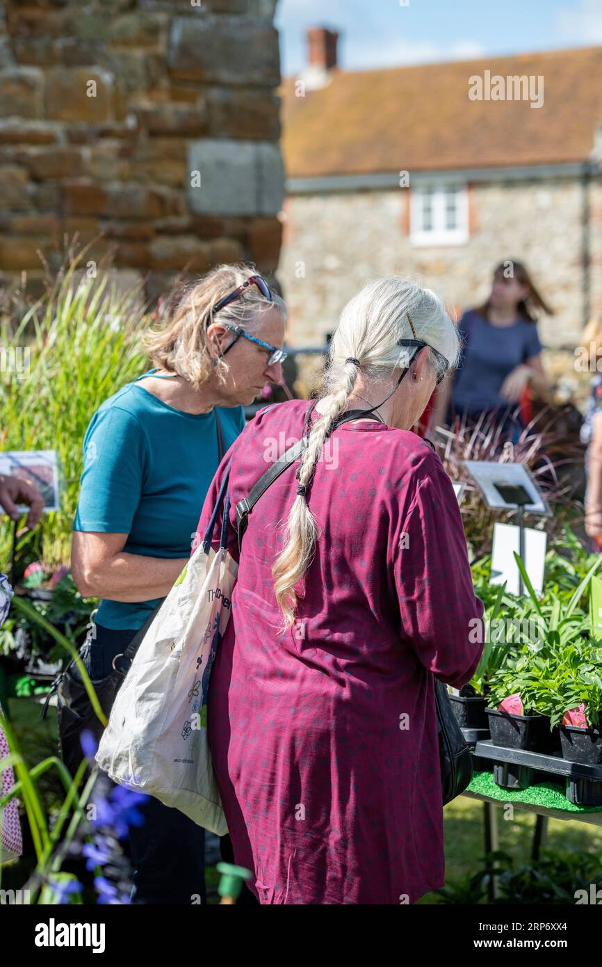 Zwei ältere Frauen oder Frauen mittleren Alters, die im Sommer gemeinsam in einem Gartencenter Gartenpflanzen kaufen. Stockfoto