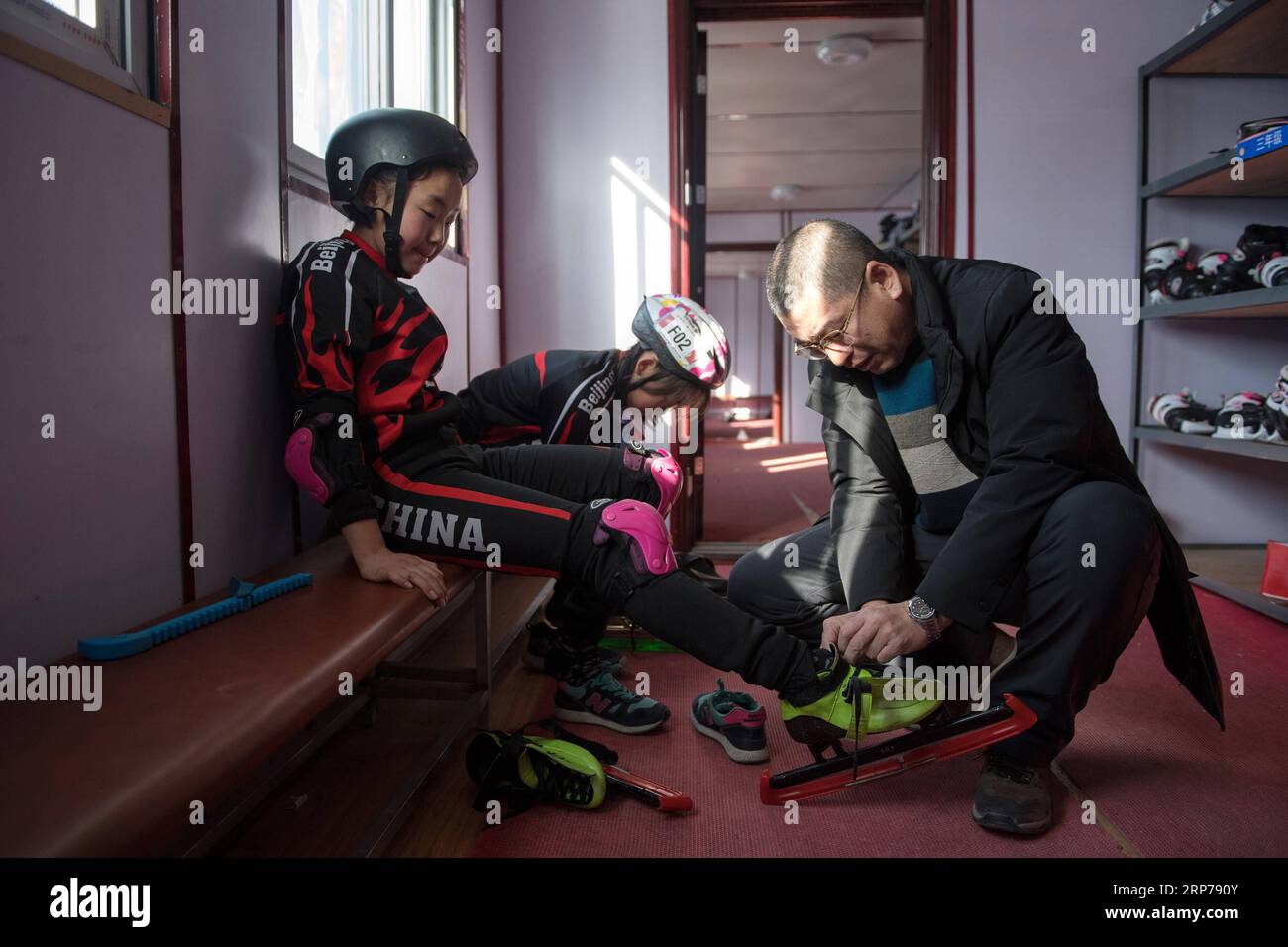 (190201) - Peking, Februar 1, 2019 (Xinhua) - Foto auf Jan. 9, 2019 zeigt, Leiterin Ding Jianpei (R) helfen, ein Student mit der Schlittschuhe für eine Trainingseinheit bei Taipingzhuang zentrale Grundschule, im Landkreis Yanqing von Peking, der Hauptstadt von China. Taipingzhuang zentrale Grundschule direkt am Fuße des Xiaohaituo Bergen, wo die Veranstaltungsorte für Beijing 2022 Olympischen Winterspiele im Bau befinden. Die Lehrer der Taipingzhuang zentrale Grundschule haben eine experimentelle Ackerland in eine saisonale Eisbahn für die Schüler hier lernen, Skaten seit 2016 gedreht. Die Stockfoto