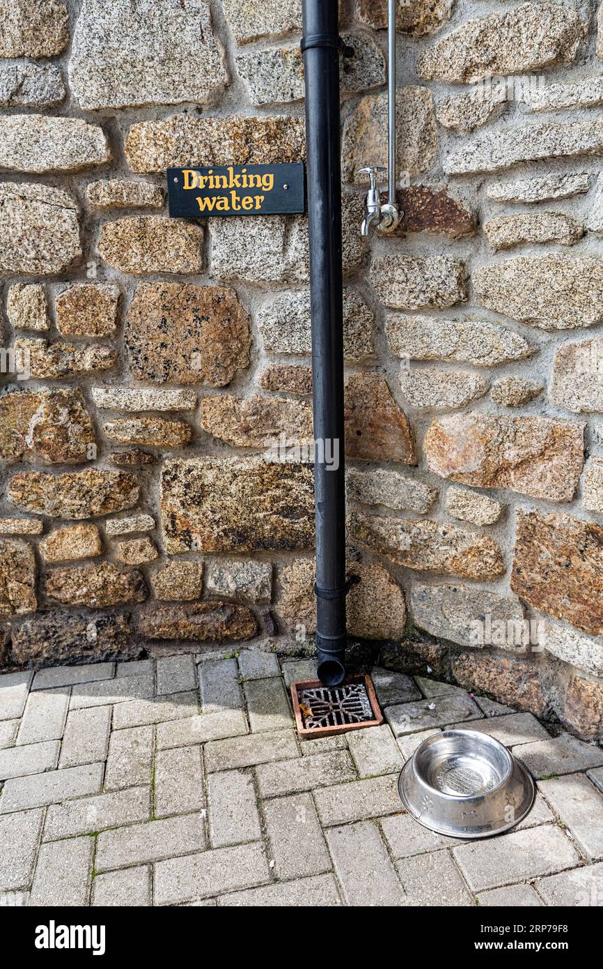 Wasserhahn und Hundeschüssel, Wasserschüssel an einer Wand mit Aufschrift Trinkwasser, Erfrischung, Versorgung für Hunde in Hitze, Hitze, England, Großbritannien Stockfoto