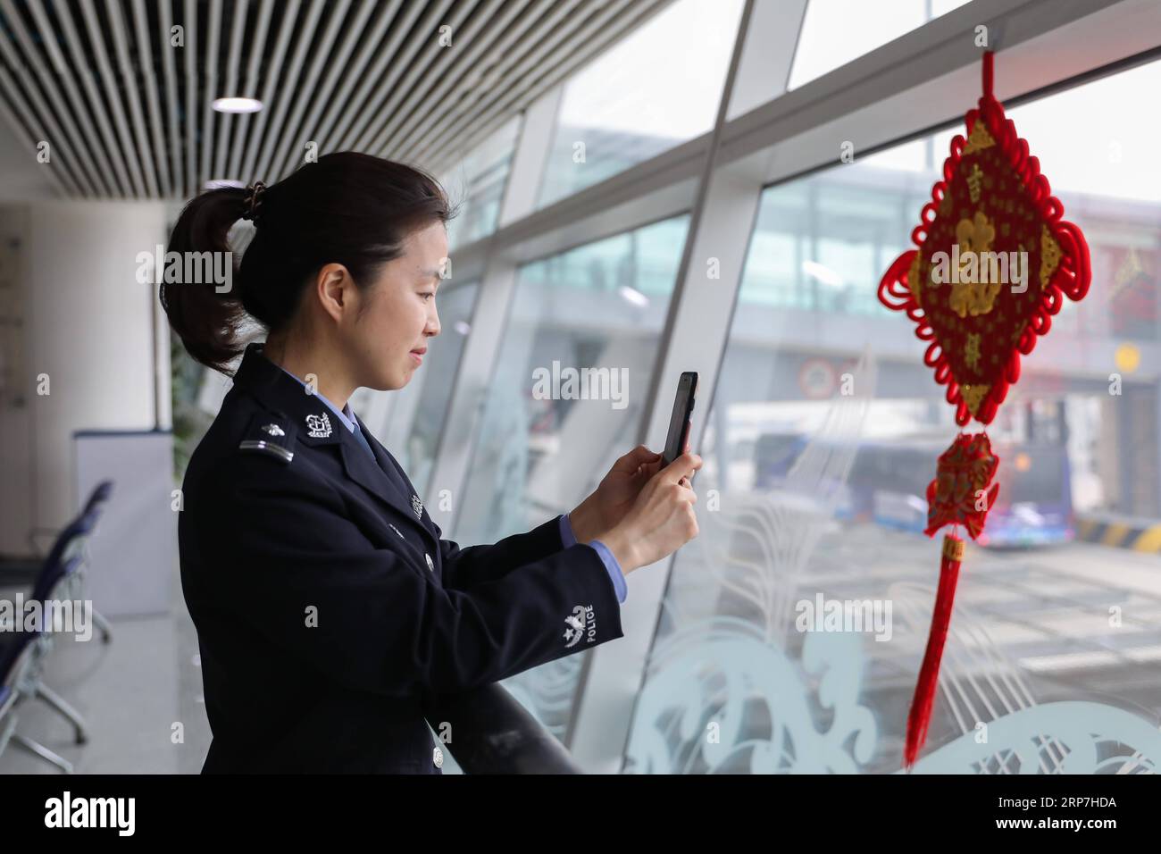 (190207) -- QINGDAO, 7. Februar 2019 (Xinhua) -- Policewoman Feng Zhe spricht mit ihrem Sohn über einen Videoanruf während einer Pause an der Einwanderungskontrollstelle des Flughafens in Qingdao, ostchinesische Provinz Shandong, 6. Februar 2019. Polizeibeamte an der Grenzkontrollstelle des Flughafens in Qingdao waren wie üblich während des chinesischen Mondneujahrs im Dienst. (Xinhua/Xie Hao) CHINA-QINGDAO-SPRING FESTIVAL-POLICE (CN) PUBLICATIONxNOTxINxCHN Stockfoto