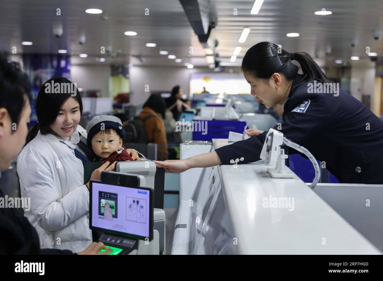 (190207) -- QINGDAO, 7. Februar 2019 (Xinhua) -- Polizistin Xu Huijuan (1. R) hilft einer Frau, die ihr Kind trägt, Informationen an der Einwanderungskontrollstelle des Flughafens in Qingdao, ostchinesische Provinz Shandong, 6. Februar 2019 zu sammeln. Polizeibeamte an der Grenzkontrollstelle des Flughafens in Qingdao waren wie üblich während des chinesischen Mondneujahrs im Dienst. (Xinhua/Xie Hao) CHINA-QINGDAO-SPRING FESTIVAL-POLICE (CN) PUBLICATIONxNOTxINxCHN Stockfoto