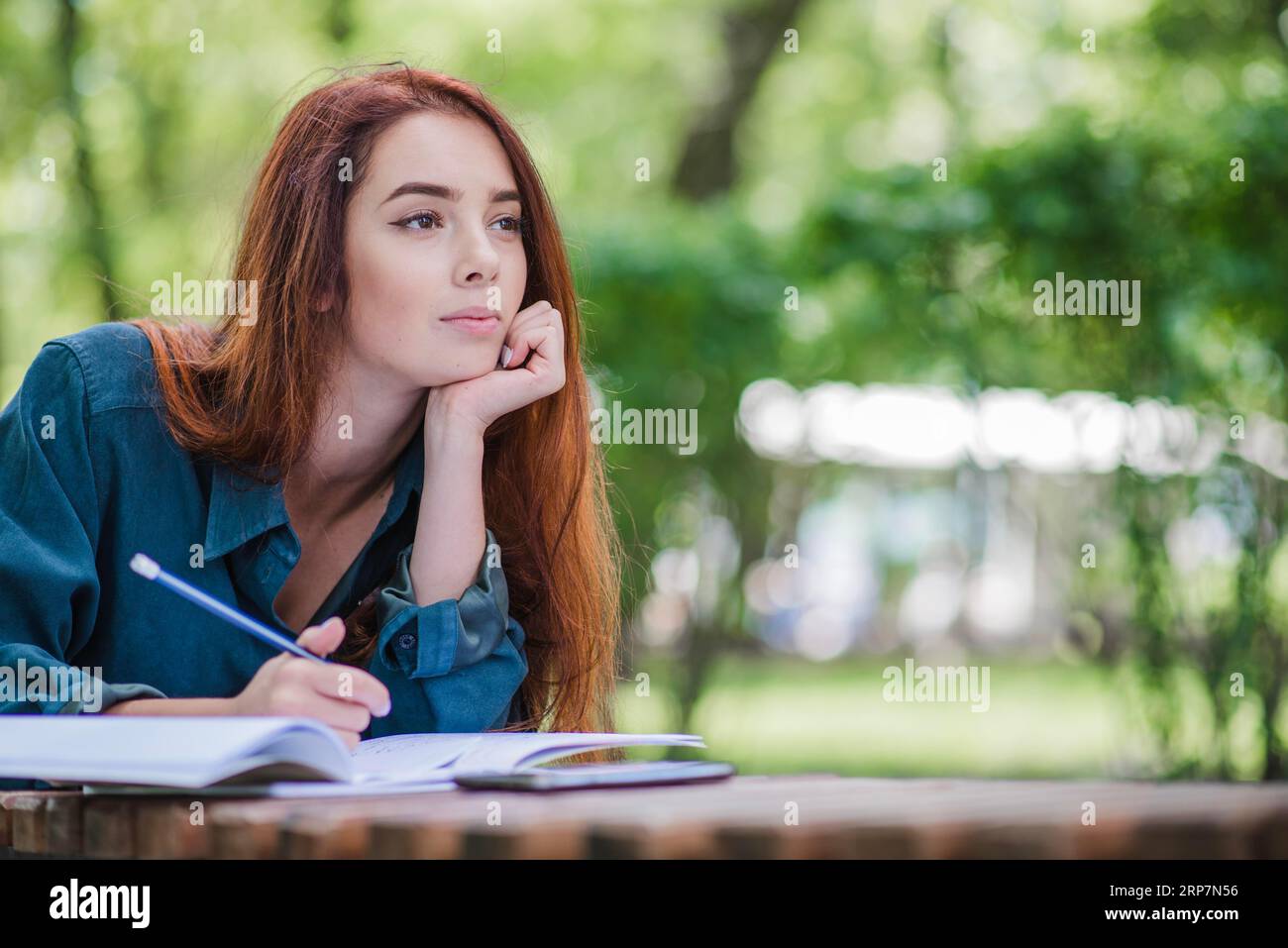 Mädchen, das am Tisch liegt und schreibt Stockfoto