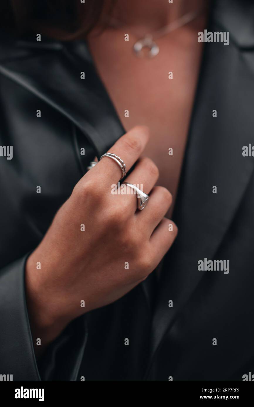 Nahaufnahme von modischen Details einer schwarzen Lederjacke und silbernen Ring-Accessoires. Schickes Outfit, Accessoires für Frauen Stockfoto