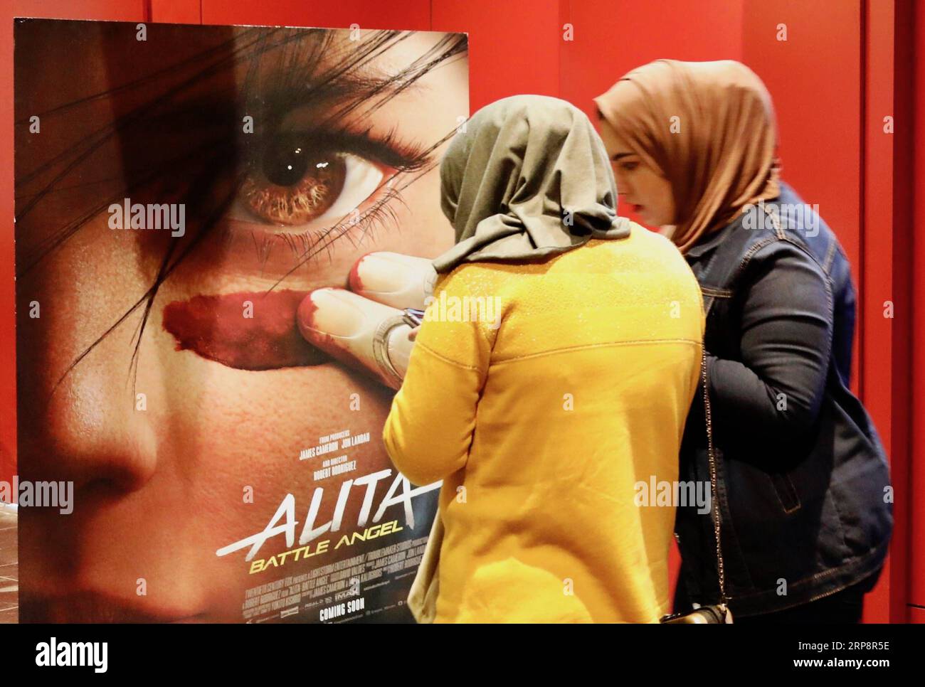 (190313) -- BAGDAD, 13. März 2019 (Xinhua) -- Foto aufgenommen am 21. Februar 2019 zeigt zwei irakische Frauen neben einem Filmplakat in einem Kino in Bagdad, Irak. ZU DEN Features: Moderne Kinos MIT mehreren Bildschirmen ziehen begeisterte irakische Kinobesucher an, während die berühmten Kinos (Xinhua/Khalil Dawood) IRAK-BAGDAD-KINO PUBLICATIONxNOTxINxCHN verschwinden Stockfoto