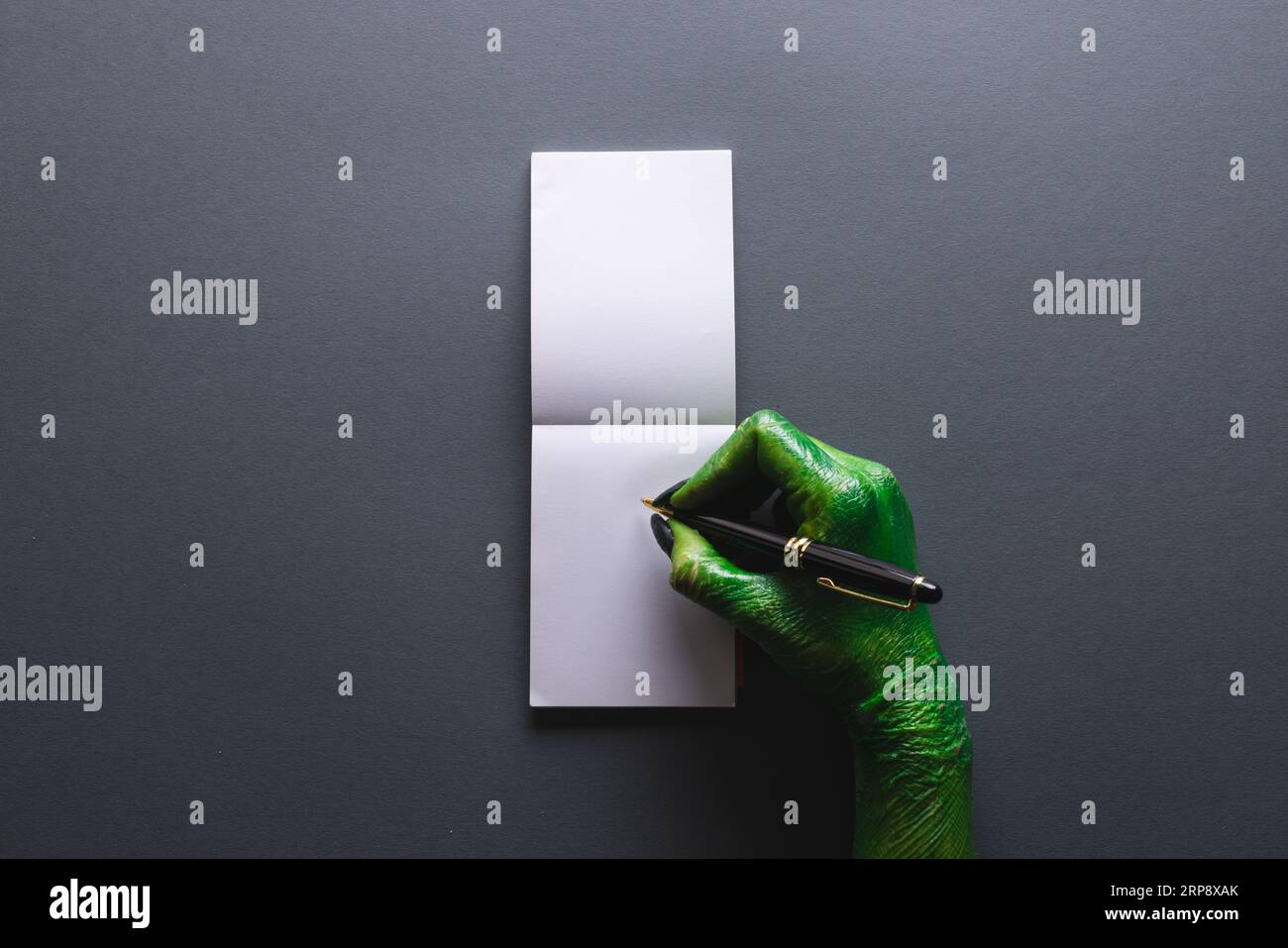 Grünes Monster Hands Schreibheft mit Kopierraum auf grauem Hintergrund Stockfoto