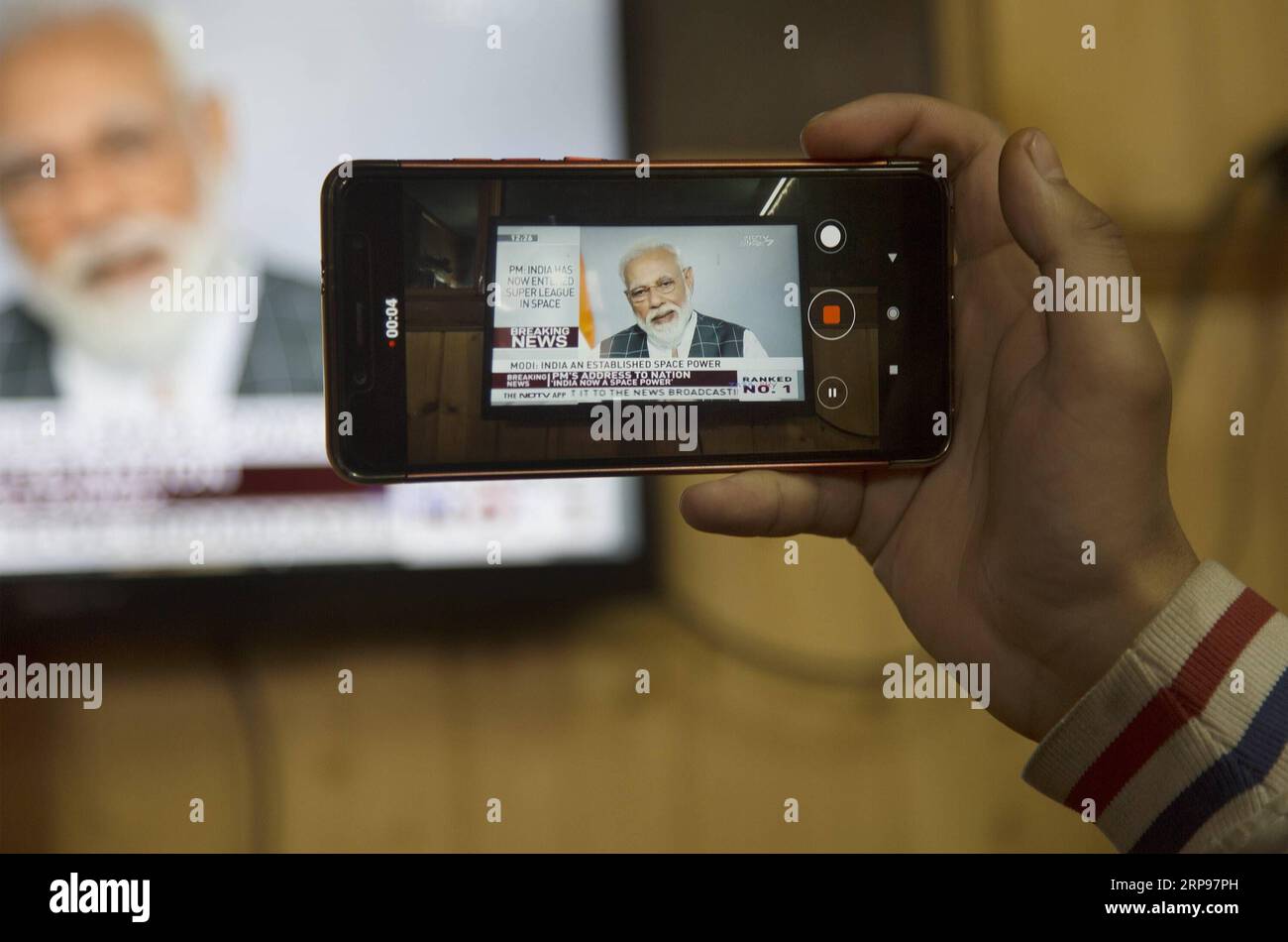 (190327) -- SRINAGAR, 27. März 2019 (Xinhua) -- A man Records the address of Indian Prime Minister Narendra Modi in Srinagar, the Summer Capital of Indian controlled Kashmir, March 27, 2019. Der indische Premierminister Narendra Modi sagte am Mittwoch in einer Überraschungsrede vor der Nation, dass indische Wissenschaftler einen Satelliten auf einer niedrigen Erdumlaufbahn (LEO) mit einer Anti-Satelliten-Waffe A-SAT abgeschossen hätten. (Xinhua/Javed dar) KASCHMIR-SRINAGAR-INDIAN PM-ADDRESS PUBLICATIONxNOTxINxCHN Stockfoto