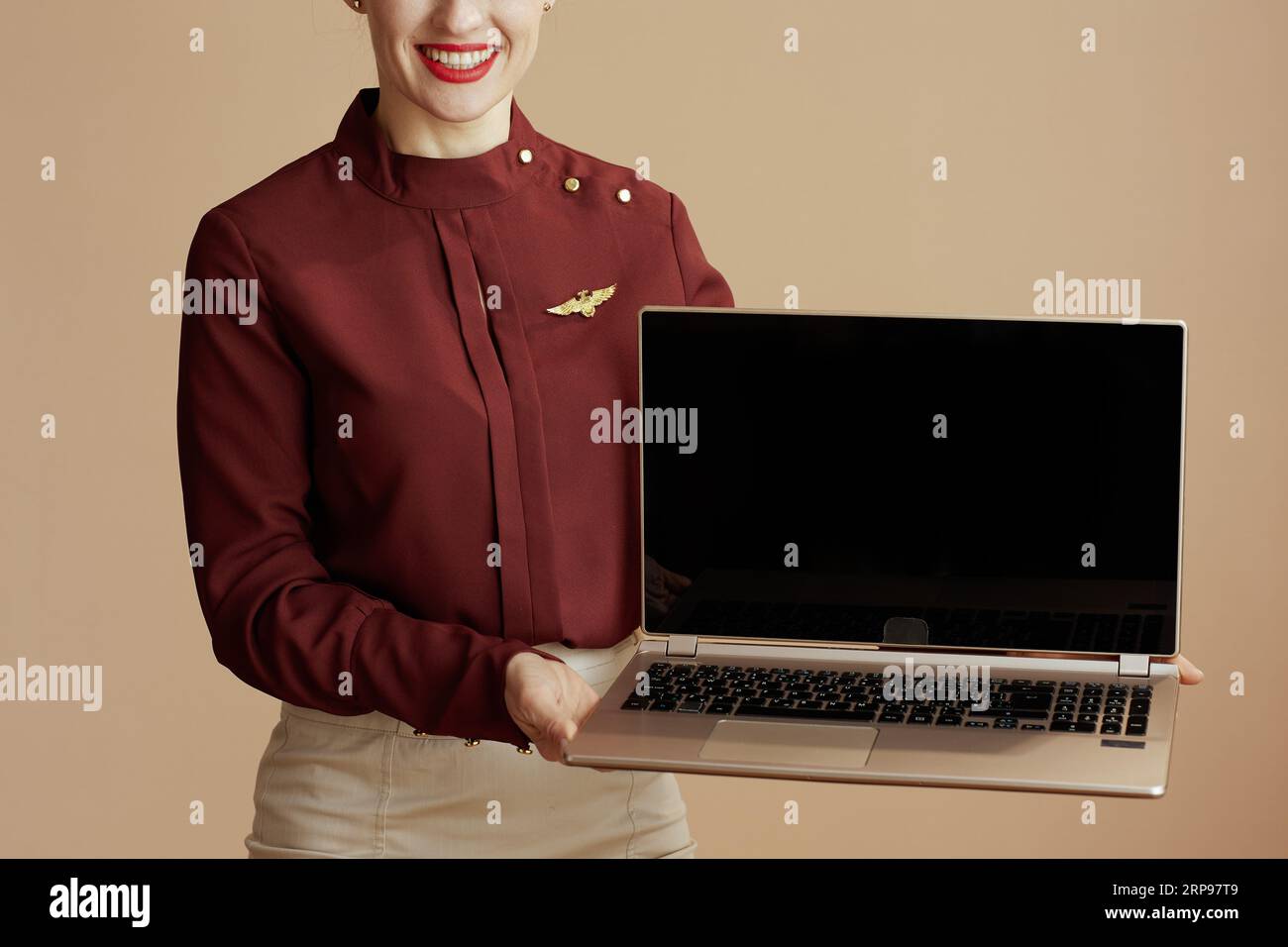 Nahaufnahme auf moderne Fluggastfrau isoliert auf beigem Hintergrund mit leerem Laptop-Bildschirm. Stockfoto