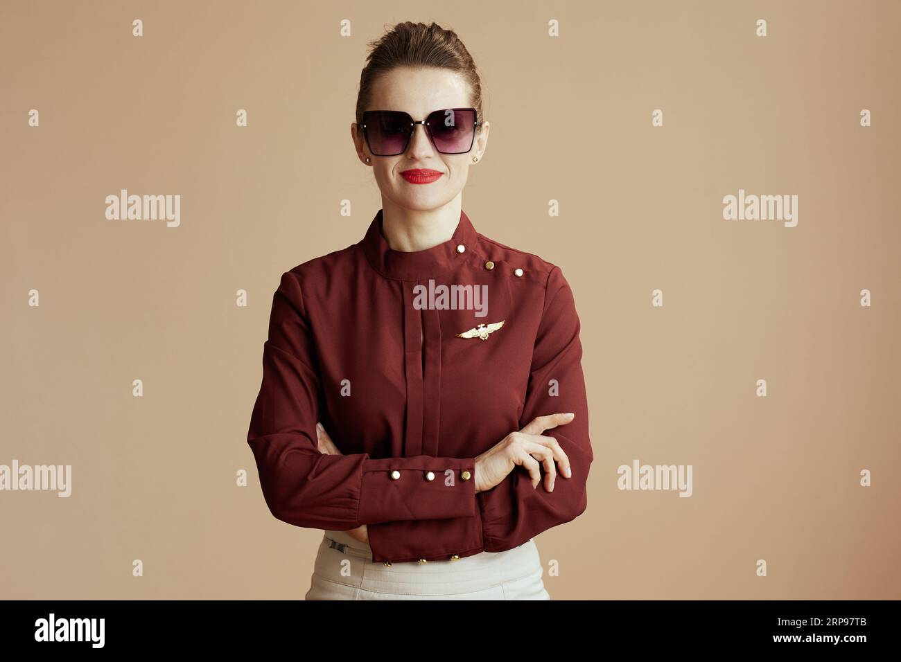 Porträt der stilvollen Luftwirtin Frau isoliert auf beigem Hintergrund mit Sonnenbrille. Stockfoto