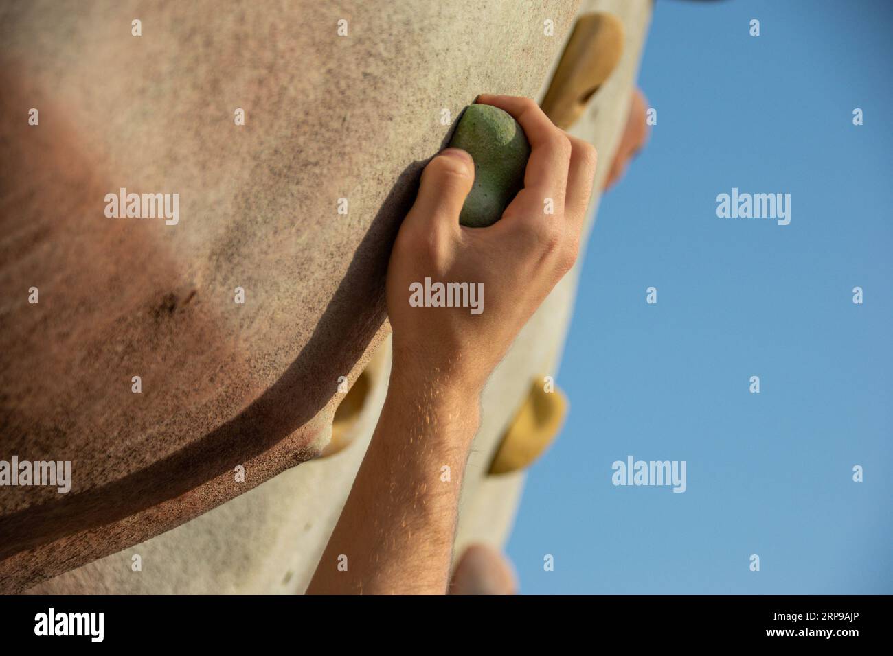 Nahaufnahme der rechten Hand eines jungen Kaukasiers, der den Griff an einer Kletterwand ergreift Stockfoto