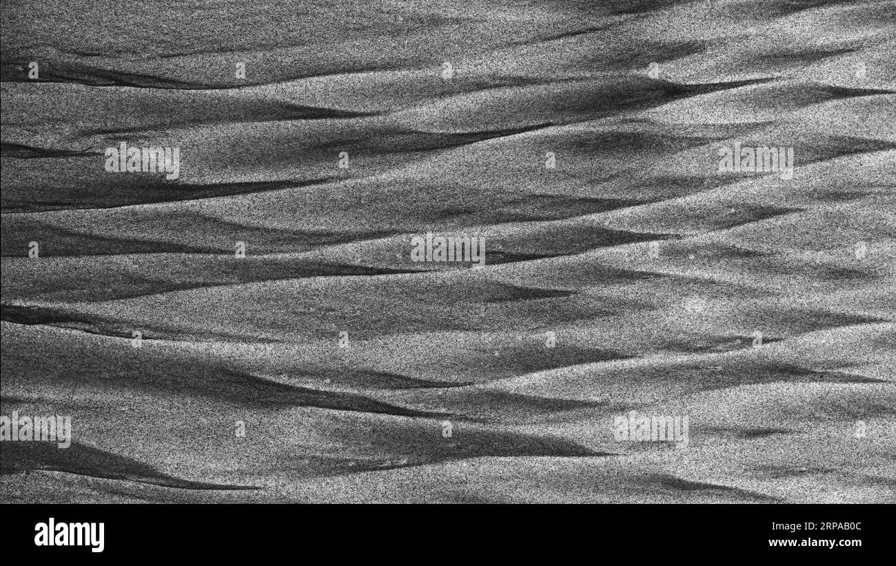 Hintergrund: Die grafische Ressource der Natur. Eine monochrome Szene aus schwarzem vulkanischem und goldenem Sand, gemischt in Diamantenformen am Meer an einem Strand Stockfoto
