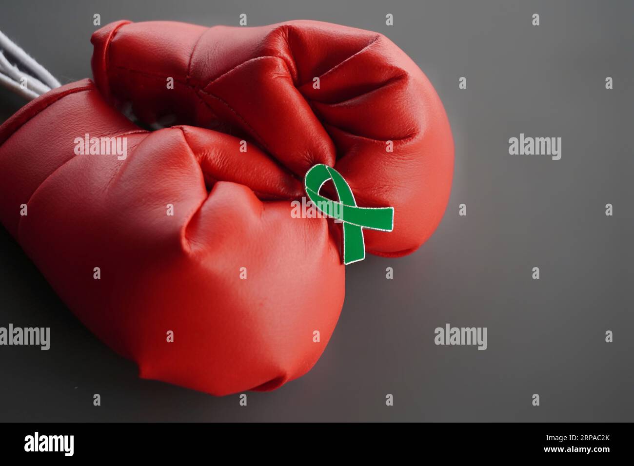 Nahaufnahme von Boxhandschuhen und grünem Band mit Kopierraum. Psychische Gesundheit und Krebsbewusstsein Stockfoto