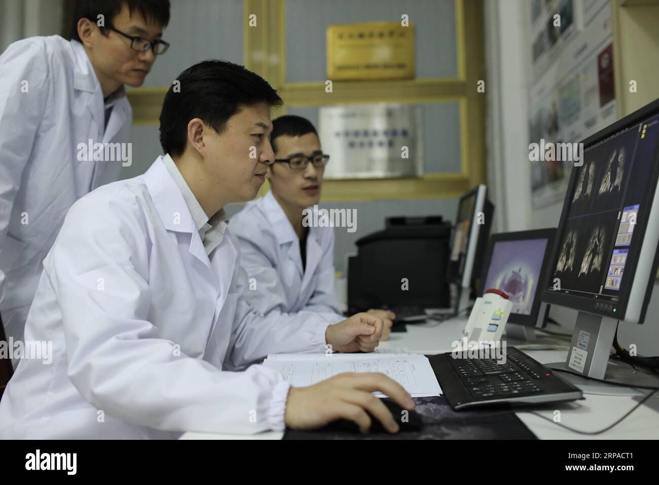 (190504) -- WUHAN, 4. Mai 2019 (Xinhua) -- Zhou Xin (C) diskutiert mit seinen Kollegen über die Qualität von menschlichen Lungenresonanzbildern am Wuhan Institute of Physics and Mathematics of Chinese Academy of Sciences in Wuhan, Hauptstadt der zentralchinesischen Provinz Hubei, 18. April 2019. Professor Zhou Xin ist stellvertretender Direktor des Wuhan Institute of Physics and Mathematics der Chinesischen Akademie der Wissenschaften, des State Key Laboratory of Magnetic Resonance and Atomic and Molecular Physics und des National Center for Magnetic Resonance in Wuhan. Er interessiert sich für Ultraschall-Magnetresonanztomographie Stockfoto