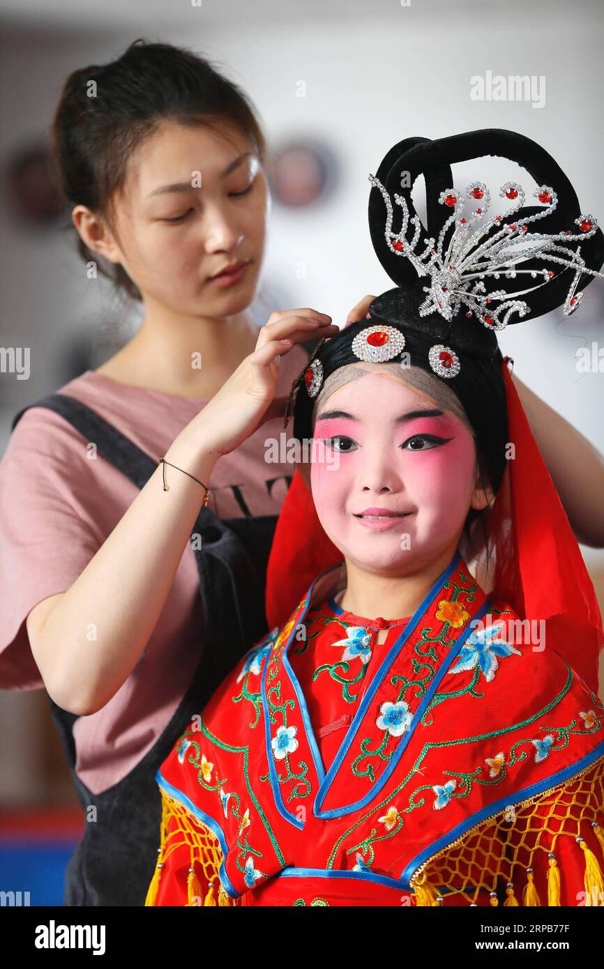 (190530) -- QINGDAO, 30. Mai 2019 (Xinhua) -- Ein Lehrer organisiert das Kopfzubehör für einen Schüler der Tongji Experimental School in Qingdao, Ostchinesische Provinz Shandong, 30. Mai 2019. Die Tongji Experimental School integriert die Peking Opera in ihre Kurse ab September 2018, um die traditionelle chinesische Kultur zu erben. (Xinhua/Liang Xiaopeng) CHINA-SHANDONG-QINGDAO-PEKING OPERA-INHERITING (CN) PUBLICATIONxNOTxINxCHN Stockfoto