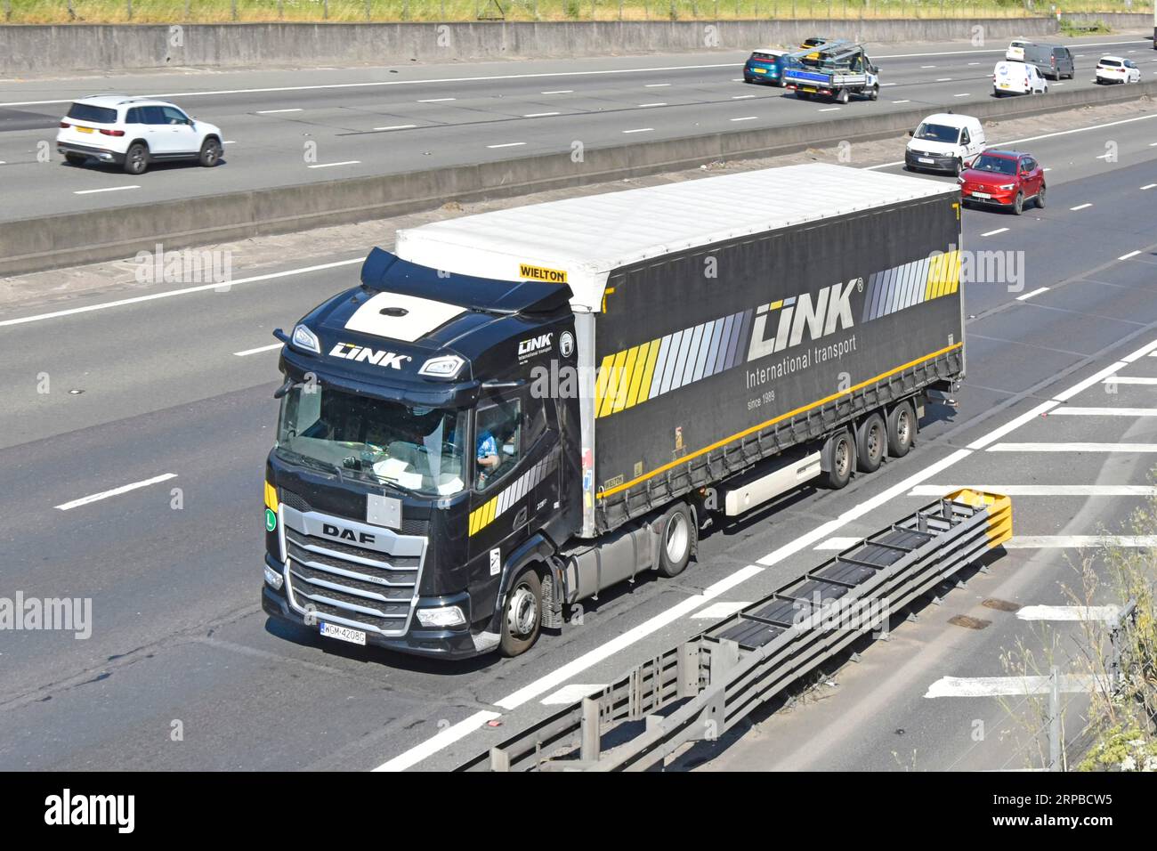 Schwarzer DAF-Lkw-Lkw-Auflieger mit Lastwagen und polnischer Wielton Group leicht zugänglicher Auflieger für Link International Transport auf der M25-Autobahn in Großbritannien Stockfoto