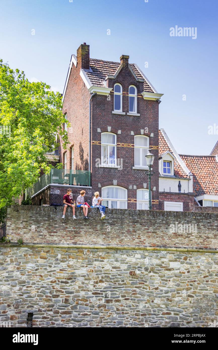 Teenager-Jungs sitzen auf der historischen Stadtmauer von Maastricht, Niederlande Stockfoto