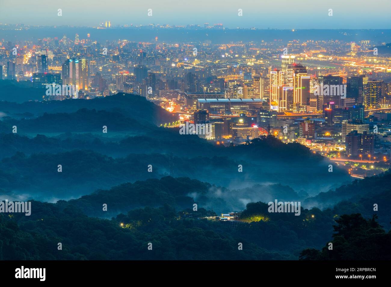 Stadtlichter und wechselnde Wolken: Ein Spektakel, das von der Spitze eines Berges aus gesehen wird. Blick auf die Stadtlandschaft vom Dajianshan Mountain, New Taipei City, Stockfoto