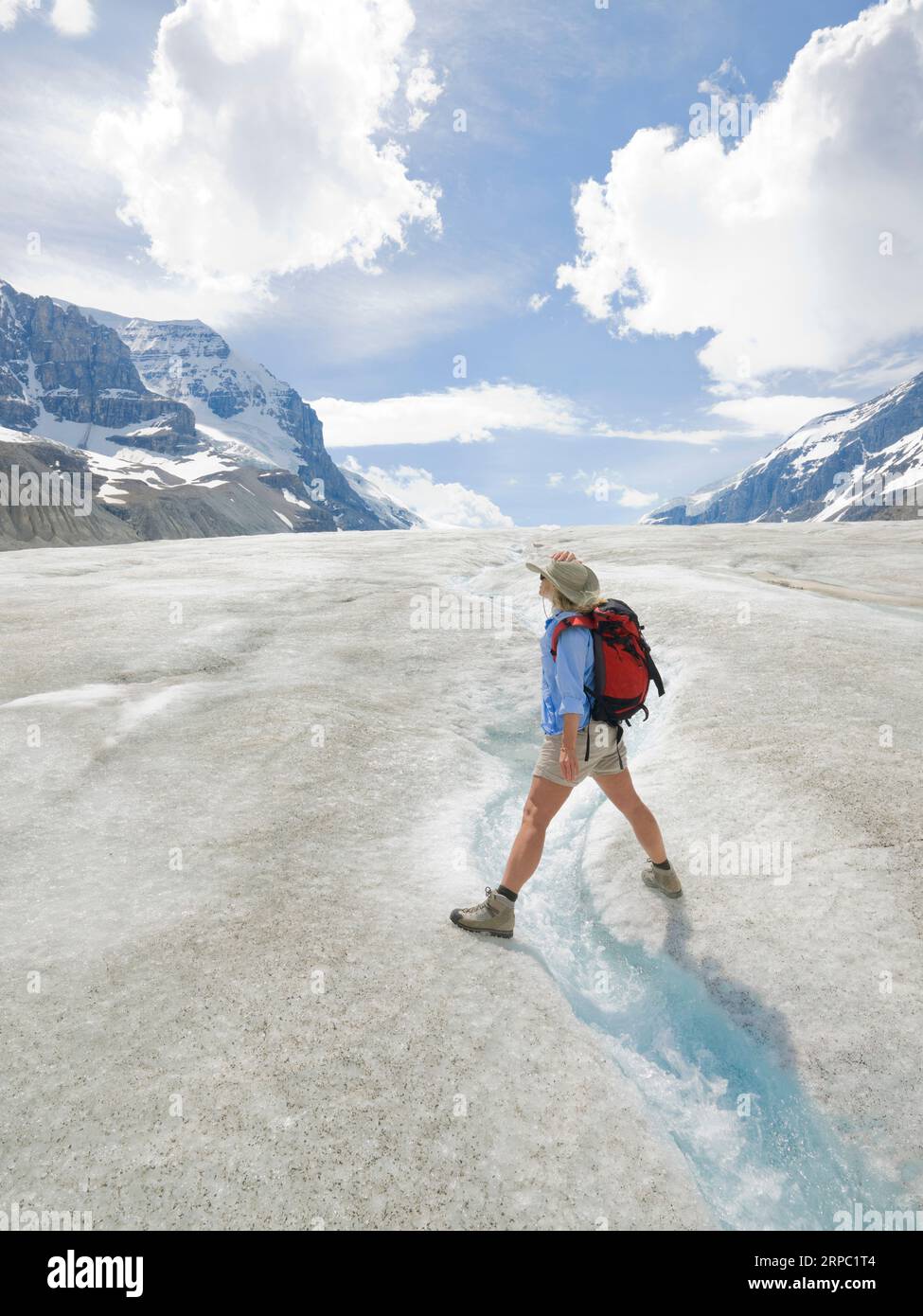 Der Wanderer erstreckt sich über den Gletscherbach auf dem Gletscher Stockfoto