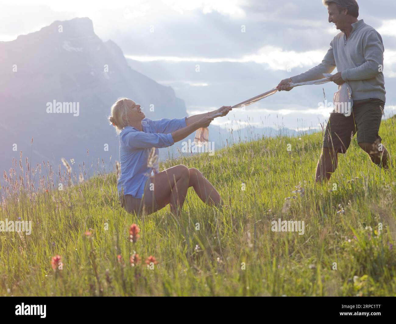 Frau und Mann spielen auf der Bergwiese Tauziehen Stockfoto