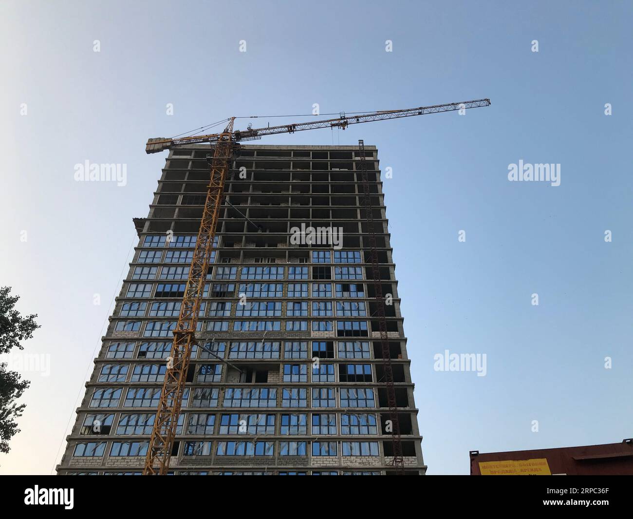Ein hohes, neues Gebäude aus Betonblockglas. Neues Haus mit Panoramafenstern. Es wird ein Haus für das Leben von Menschen und Familien gebaut. Schön und schön Stockfoto