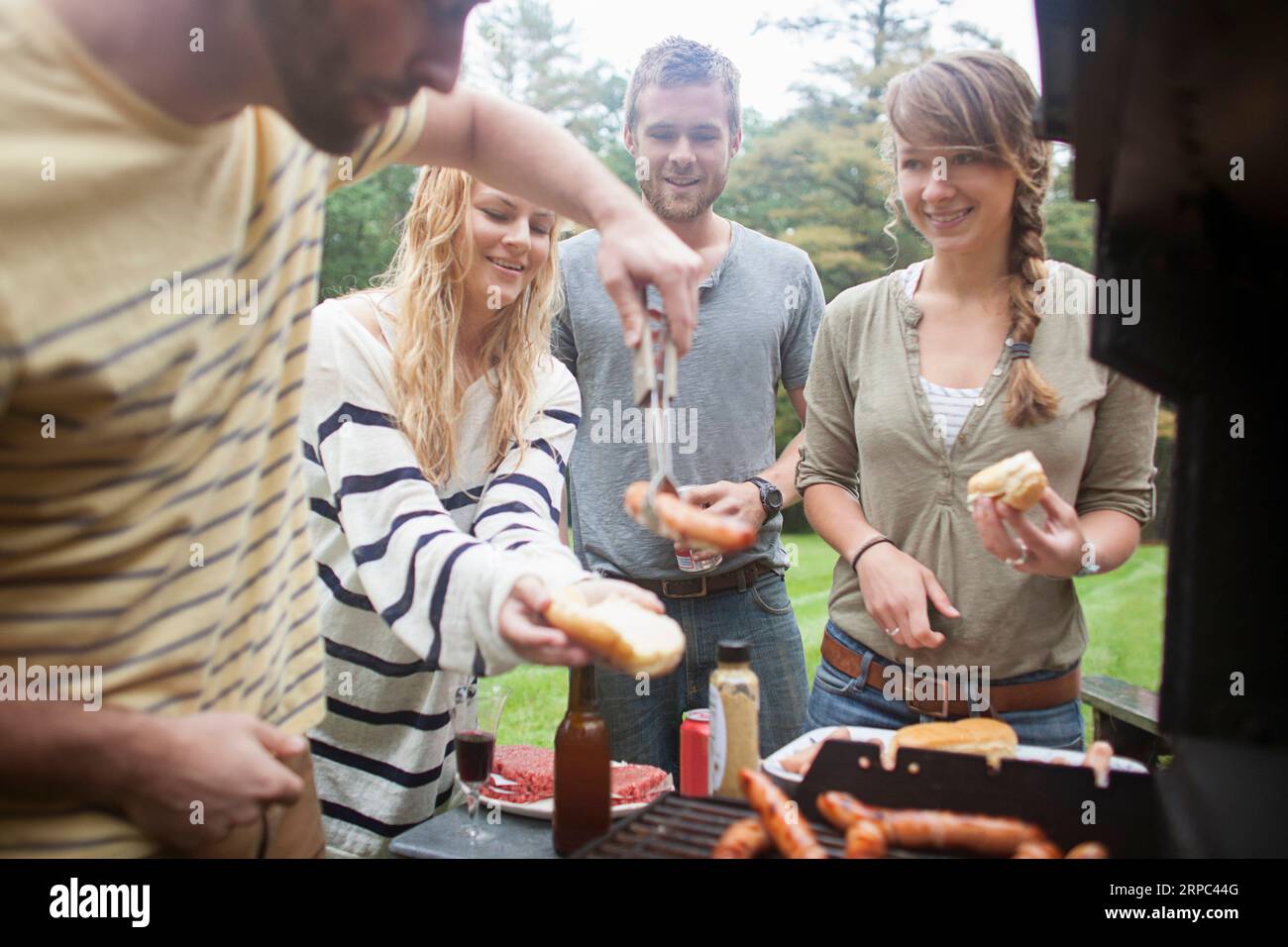 Friends grillen Hotdogs und Burger in der Nähe von Kezar Lake, Maine Stockfoto