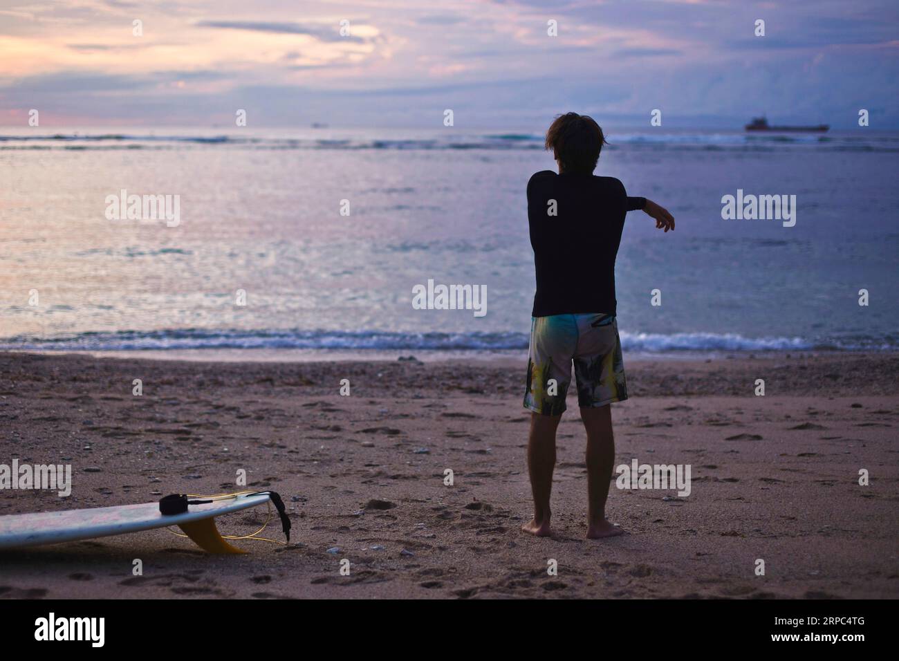 Surfen bei Sonnenuntergang erfordert ein Aufwärmen. Stockfoto