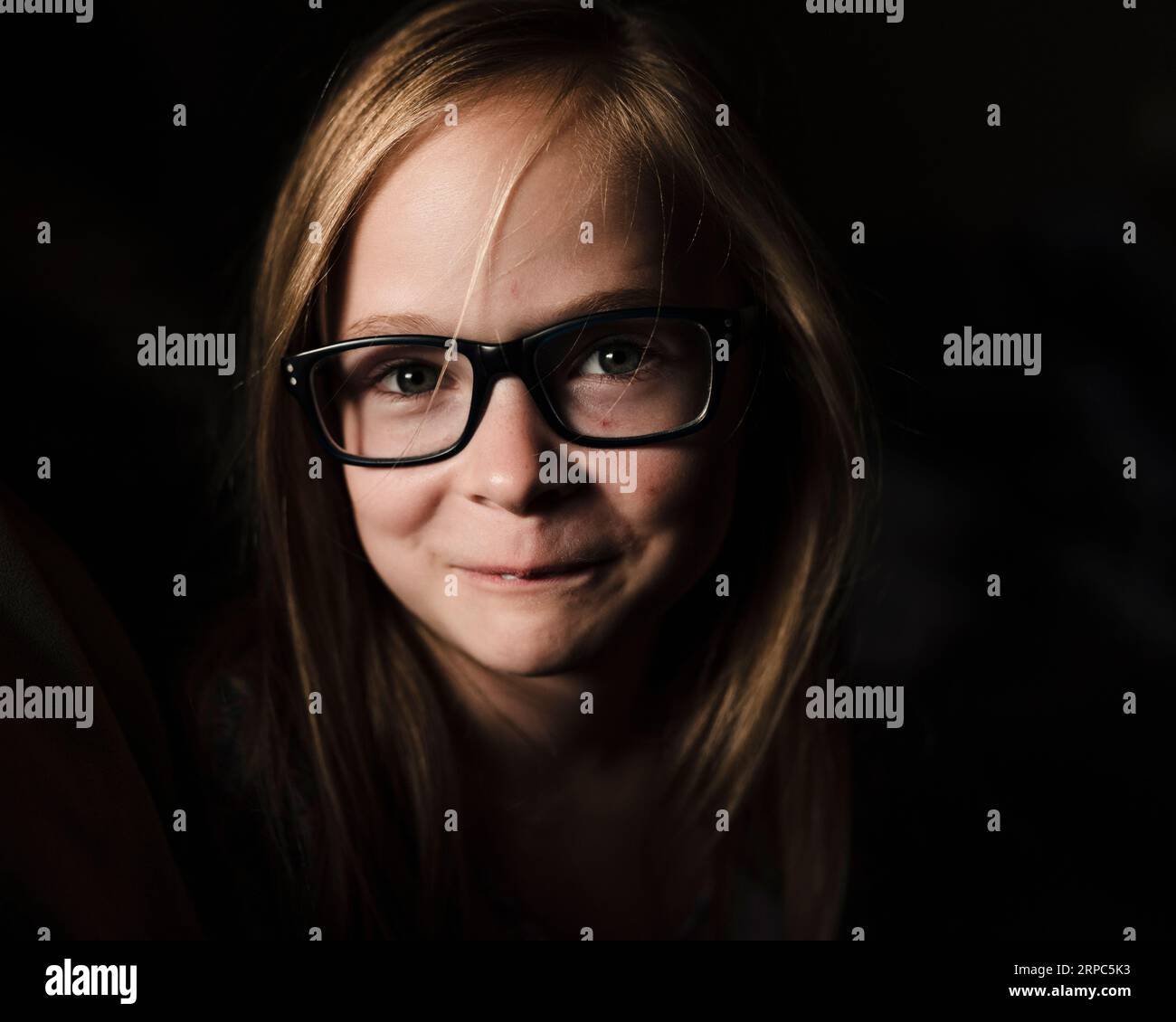 Porträt eines kleinen Mädchens mit Brille bei schwachem Licht Stockfoto