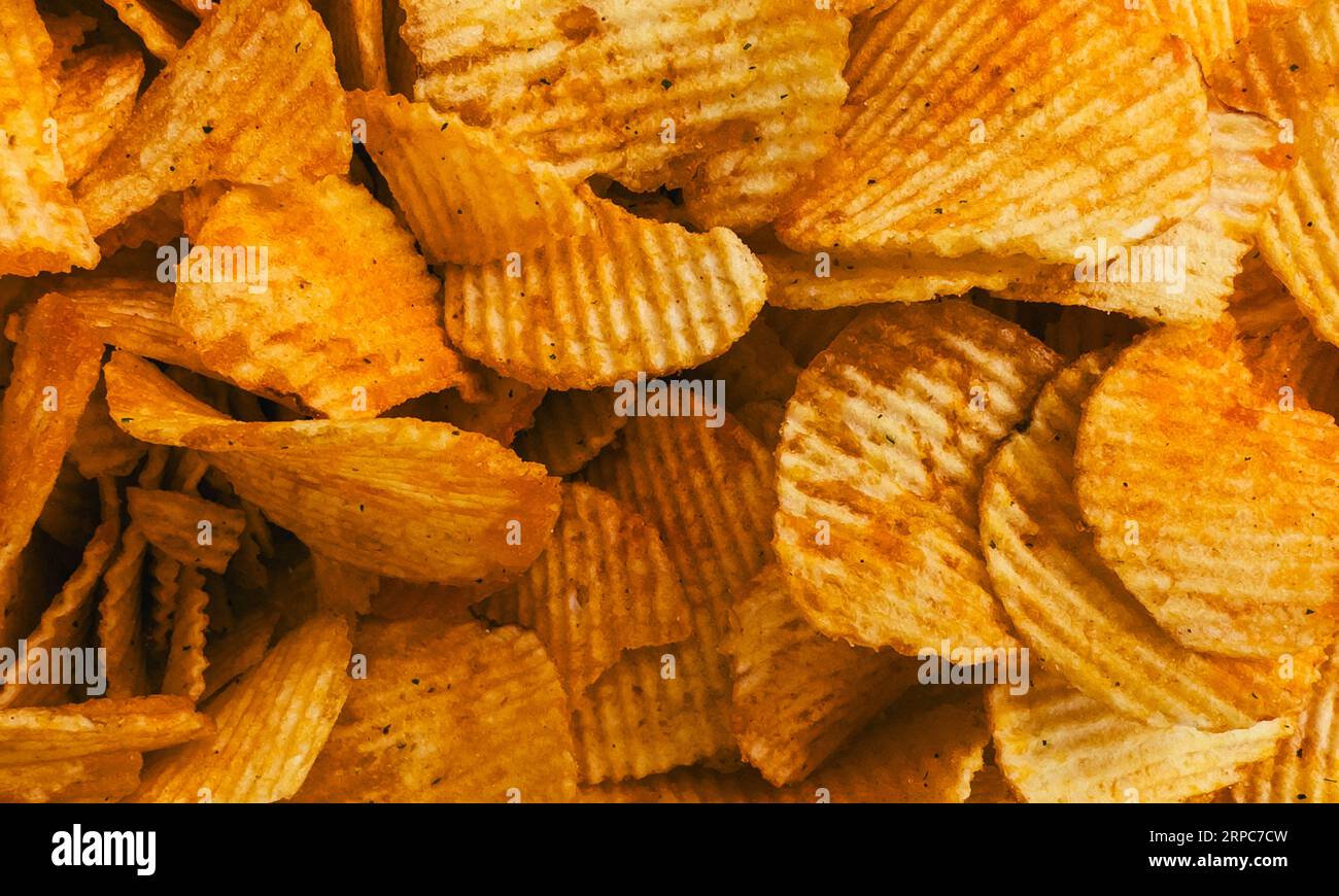 Chips-Hintergrund. Würziges Paprika-Aroma-Chips-Thema. Wellige Crisps. Stockfoto