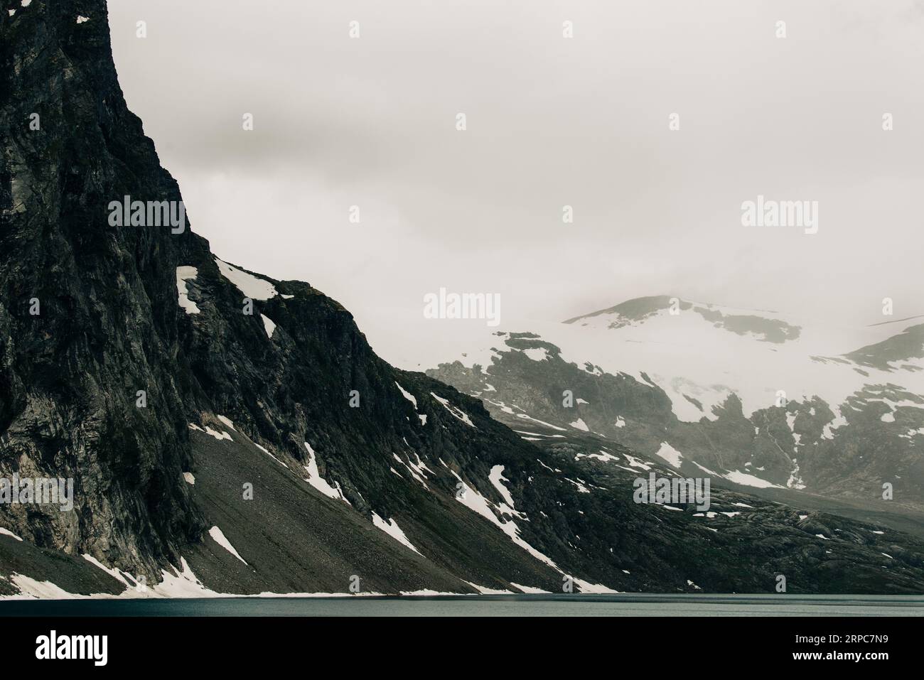 Blick auf die norwegischen Berge und den See bedeckt mit Schnee und Nebel Stockfoto