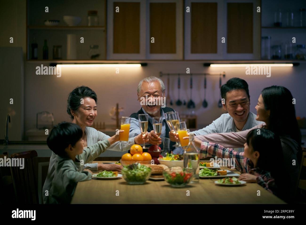 Eine asiatische Familie aus drei Generationen zu Hause, die den Urlaub mit einem Toast feiert Stockfoto