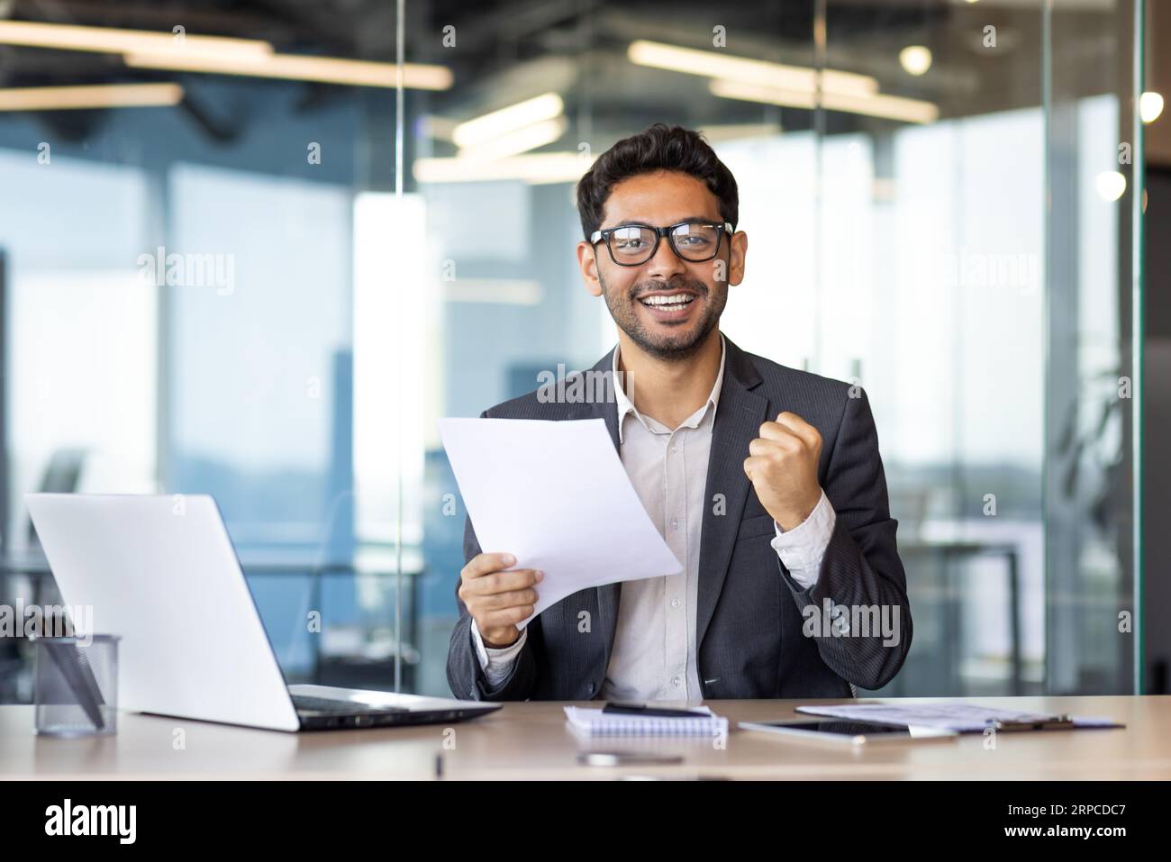 Porträt eines erfolgreichen arabischen Finanziers, erfahrener Geschäftsmann, der lächelt und die Kamera anschaut, Finanzbericht in Händen hält, Mann, der mit Erfolgen zufrieden ist, Triumphsieger-Geste. Stockfoto