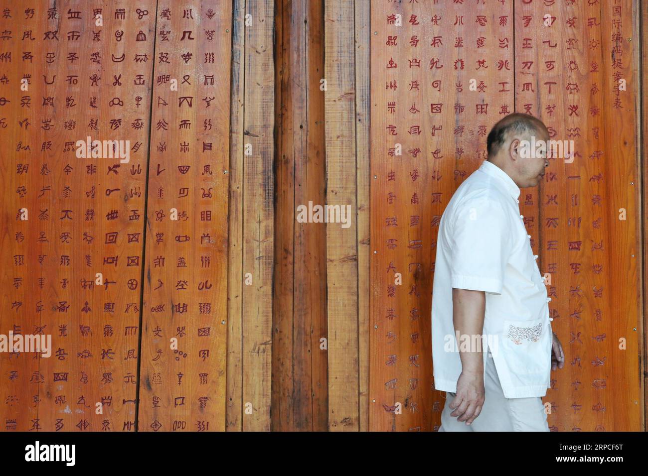 (190703) -- SANDU, 3. Juli 2019 -- der Kulturforscher Wei Shizhao spaziert an einer Gedenktafel mit Shui-Schriftzeichen in einem lokalen Shui-Schriftkulturinstitut im Sandu County, Provinz Guizhou im Südwesten Chinas, 3. Juli 2019. Wei lernte schon in seiner Kindheit das Shui-Skript. Bis jetzt haben seine modernen chinesischen Übersetzungen von Texten in Shui-Schrift fast drei Millionen Zeichen betragen. Die Shui-Schrift ist das einzigartige piktographische Schreibsystem, das von den Shui-Leuten im Südwesten Chinas verwendet wird, um Aufzeichnungen über ihre Kultur zu führen. Wie die bronzenen und orakelknocheninschriften des alten China, die Shui s Stockfoto