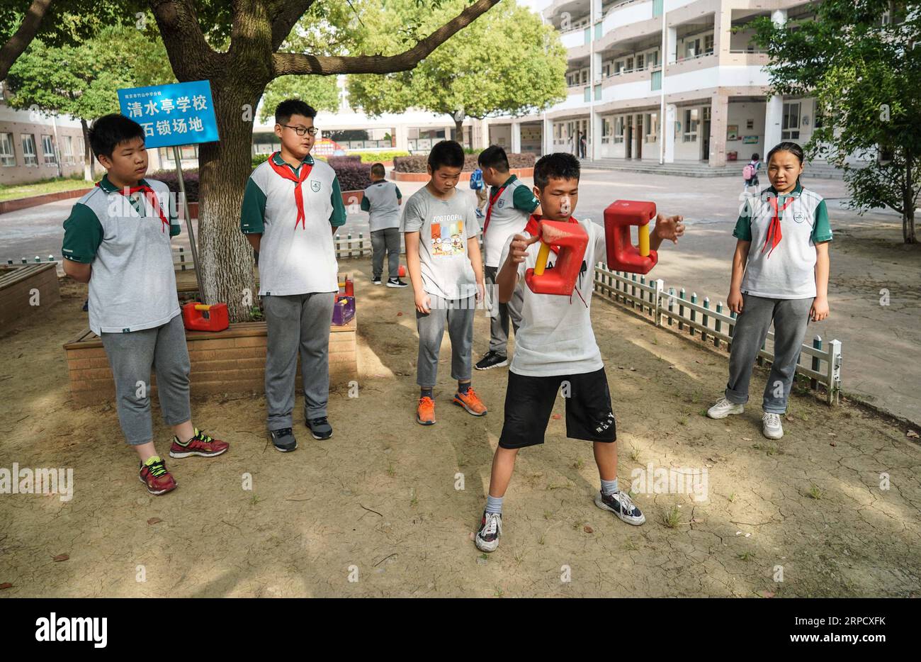 (190715) -- NANJING, 15. Juli 2019 -- Ma Guoliang (2. R) übt Shisuo in der morgendlichen Aktivitätsklasse an der Qingshuiting Primary School in Nanjing, ostchinesische Provinz Jiangsu, 5. Juni 2019. Die Schule hat einen Shisuo-Club mit 12 Schülern von der dritten bis zur sechsten Klasse. Shisuo (Steinschloss), eine Steinhantel in Form eines alten Vorhängeschlosses, wird normalerweise in der traditionellen chinesischen Trainingsroutine gesehen. Mit Hunderten von Workout-Moves kann Shisuo nicht nur die Kraft steigern, sondern auch die Koordination von Händen, Augen und Körper fördern. Shisuo geht auf die Tang-Dynastie zurück, in der s Stockfoto