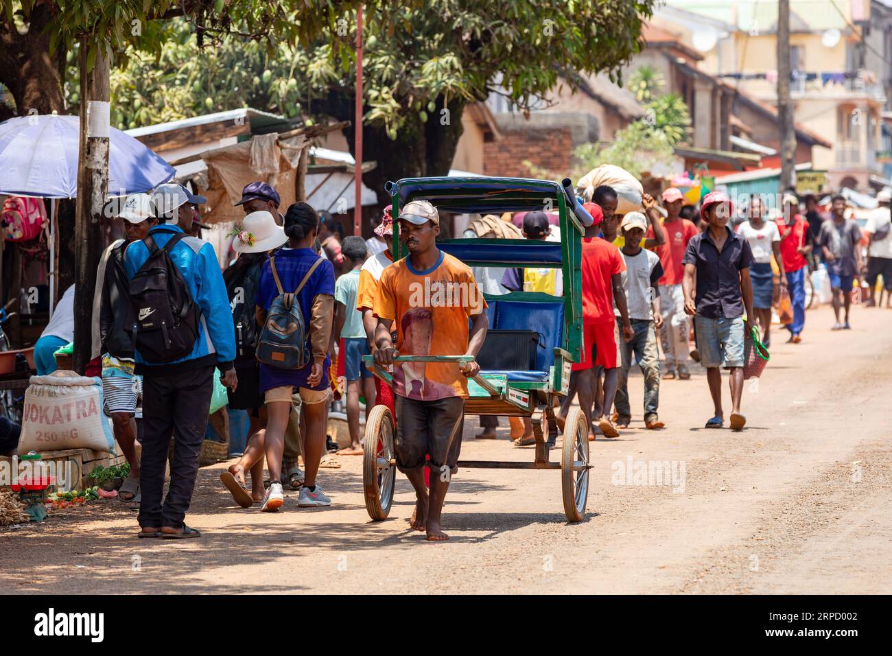 Mandoto, Madagaskar - 2. November 2022: Rikscha-Läufer stürzt mit einem kleinen Holzwagen durch die überfüllten Straßen. Eine handgeführte Rikscha, angetrieben von einem ru Stockfoto